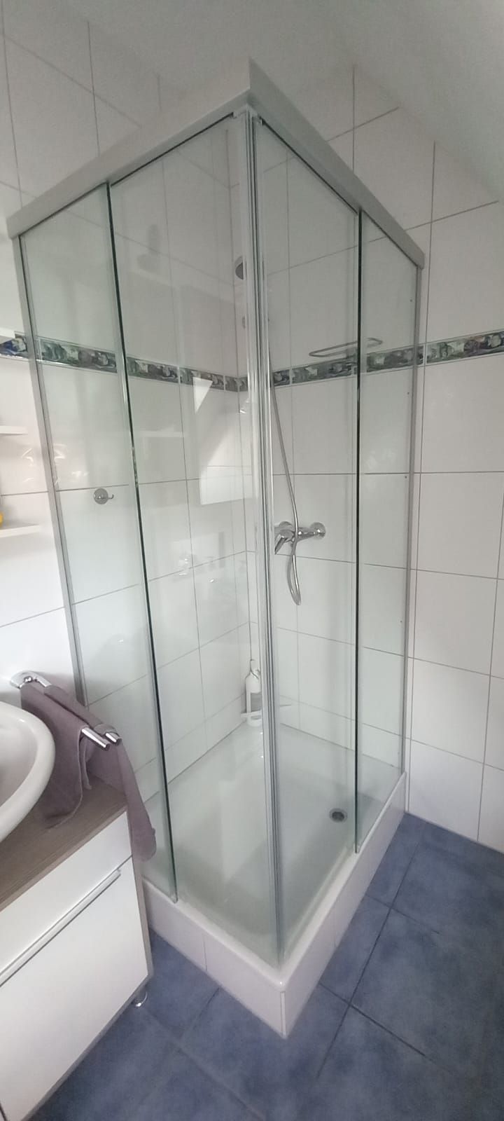 Box doccia angolare in vetro con pannelli satinati e piastrelle bianche in bagno