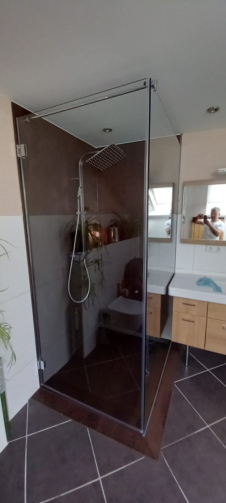 Bagno moderno con box doccia in vetro, piastrelle scure sul pavimento e mobile lavabo sulla destra