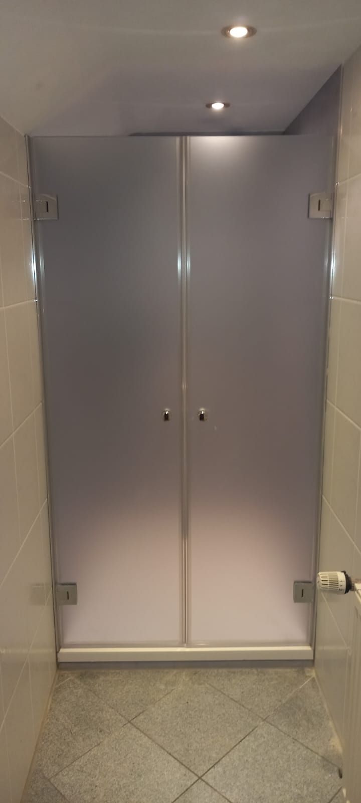 Piccolo corridoio con doppie porte chiuse, pavimento piastrellato e faretti incassati nel soffitto.