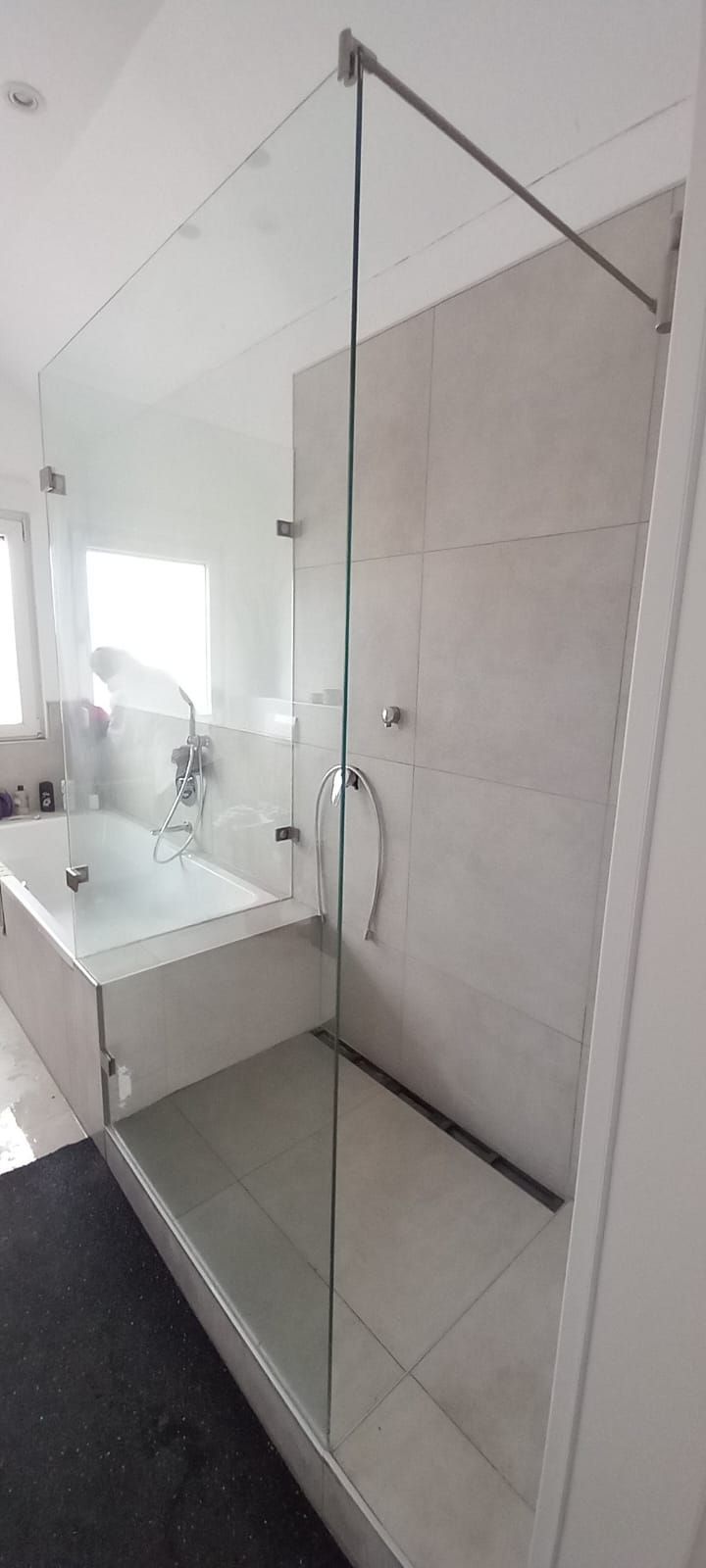 Box doccia in vetro accanto a un lavabo bianco con mobile in un bagno moderno