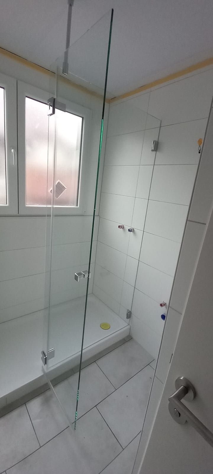 Bagno piccolo con piastrelle bianche, box doccia in vetro e luce naturale dalla finestra
