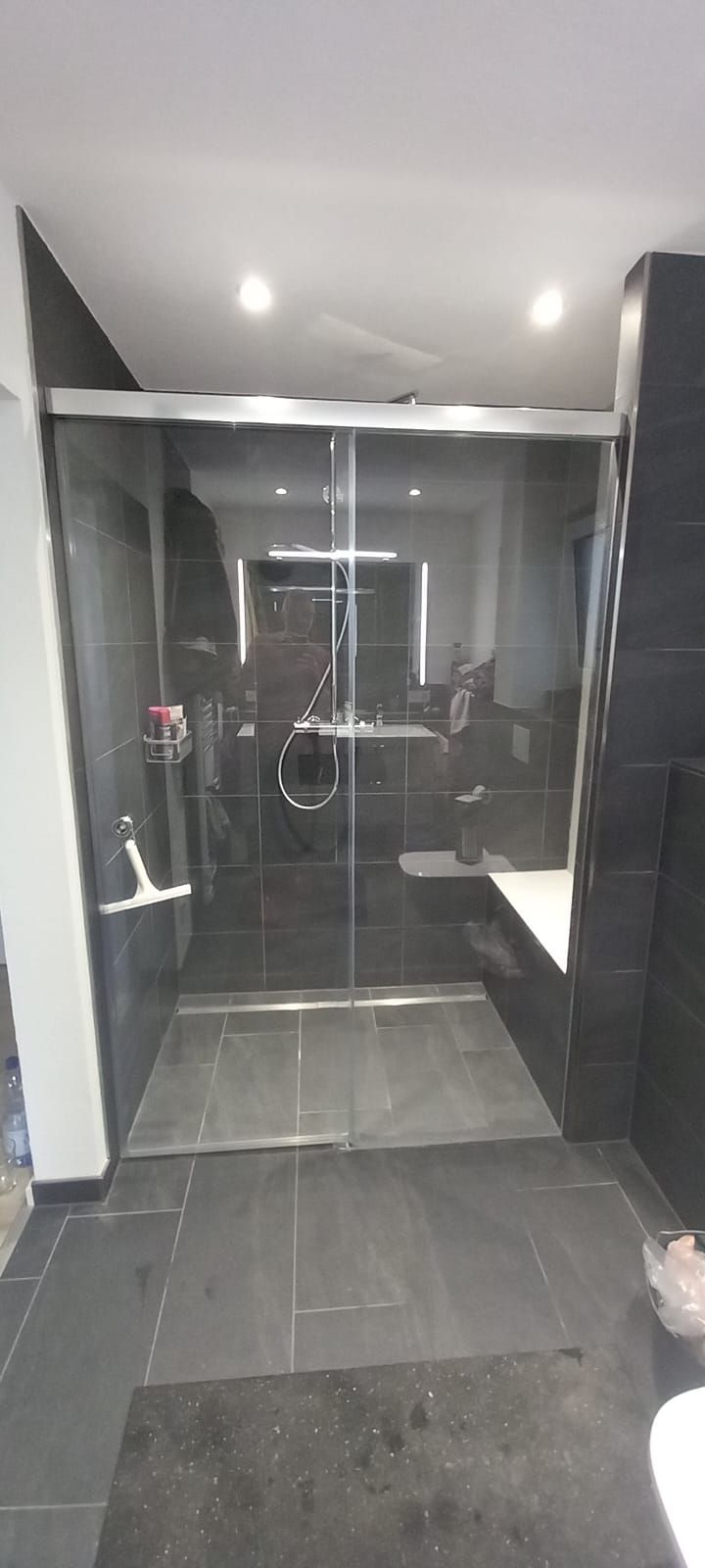 Bagno moderno con doccia in vetro, pavimento in piastrelle scure e faretti a incasso nel soffitto