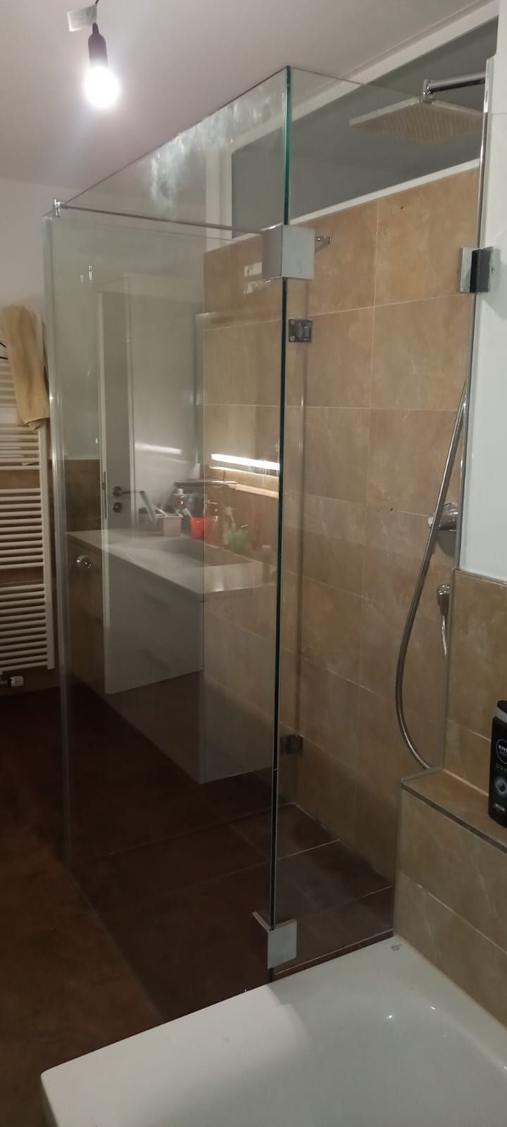 Bagno moderno con box doccia in vetro, parete rivestita di piastrelle beige e lavabo in primo piano