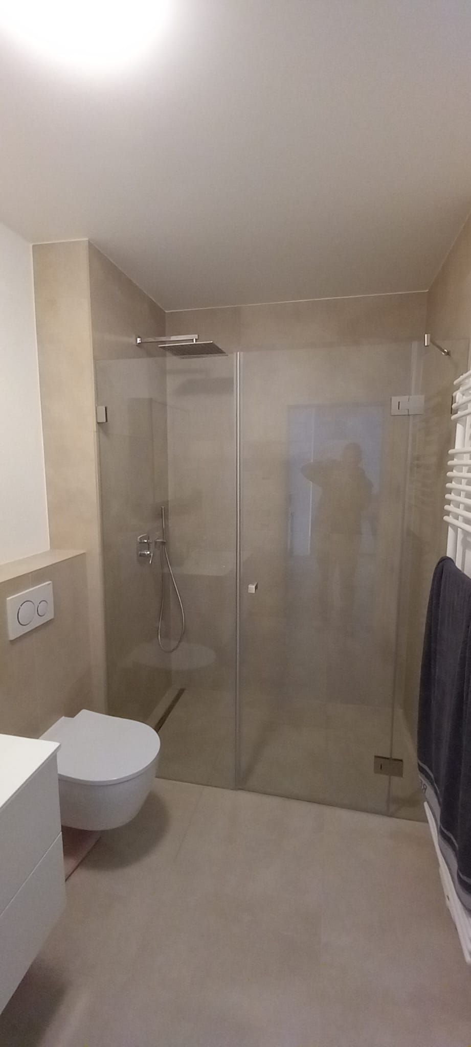 Bagno moderno beige con doccia in vetro, WC sospeso e scaldasalviette a parete