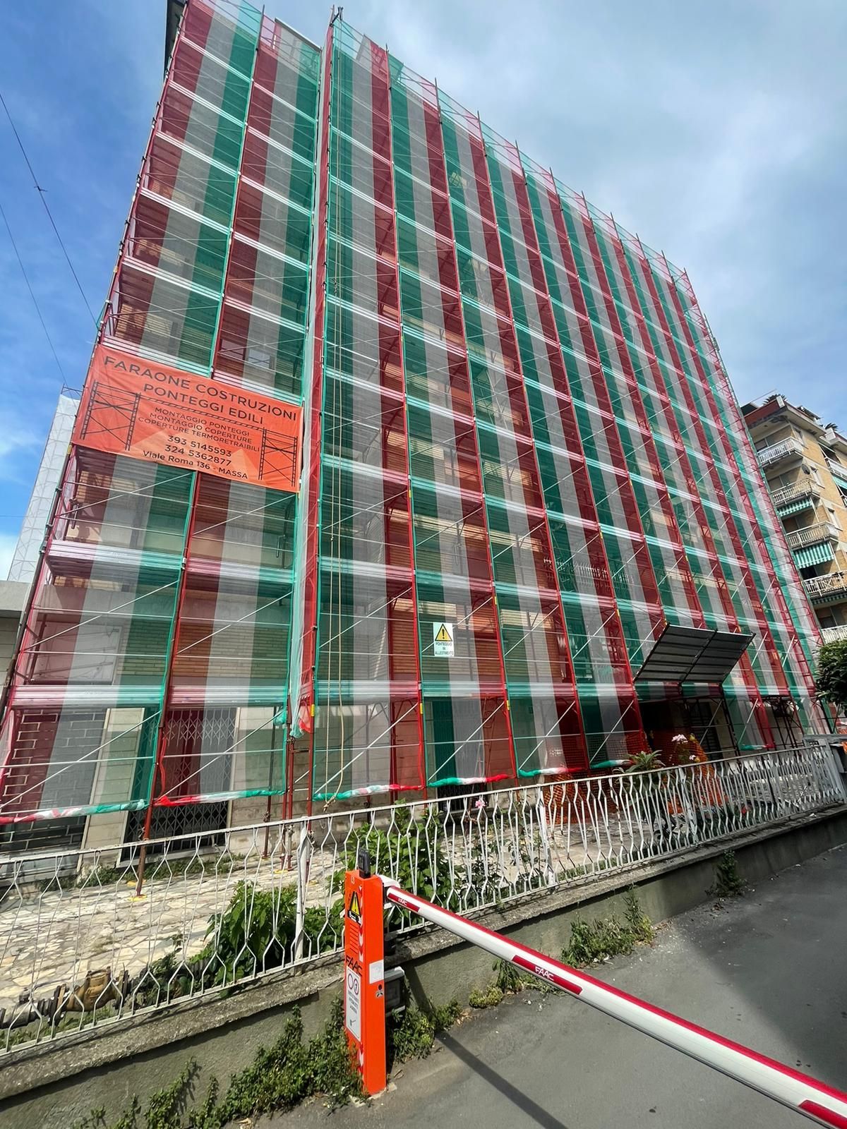 Un grande edificio con impalcature viene dipinto di rosso e verde.