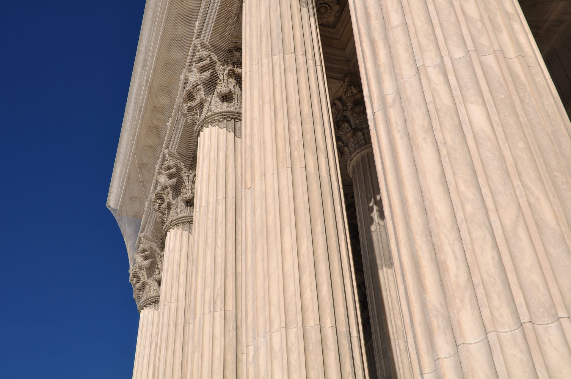 Close-up of tall marble columns and ornate stone details against a clear blue sky