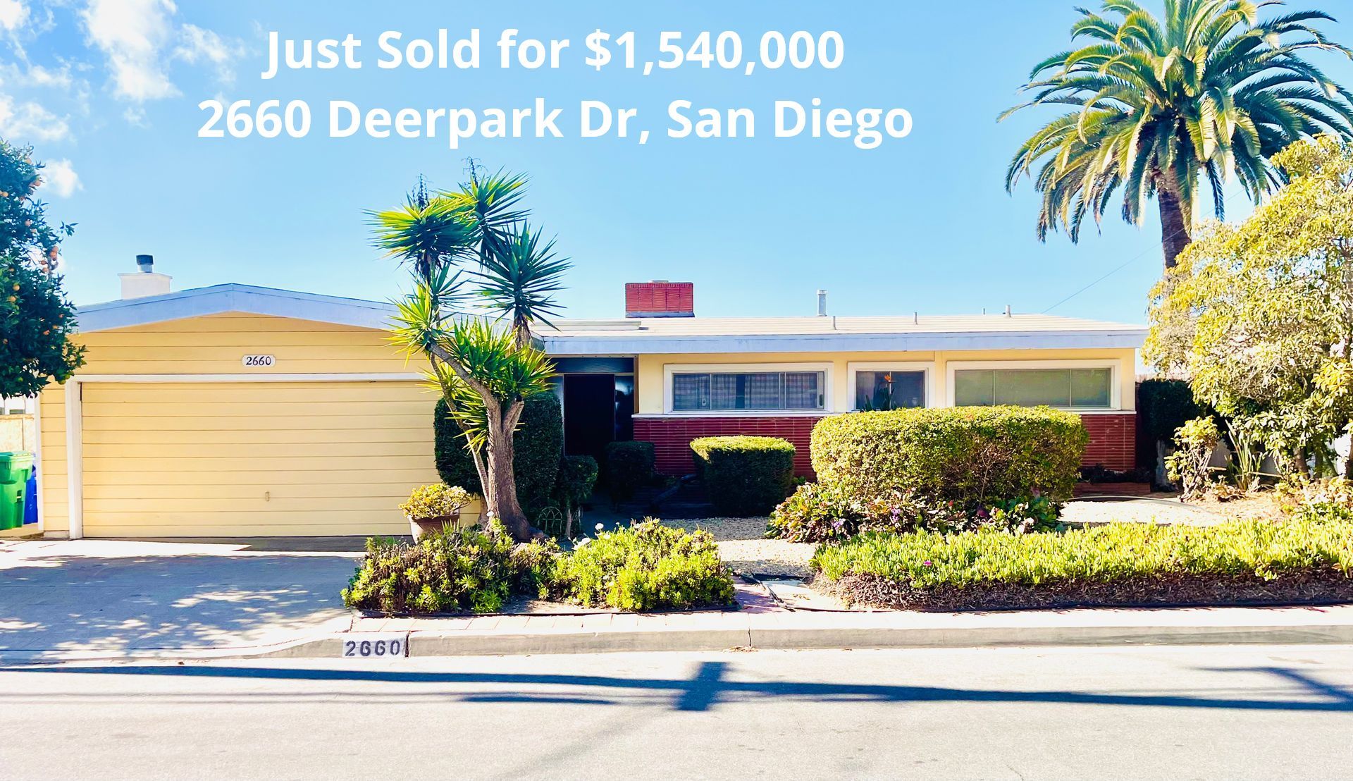 Single-story yellow house with palm trees and sign: 