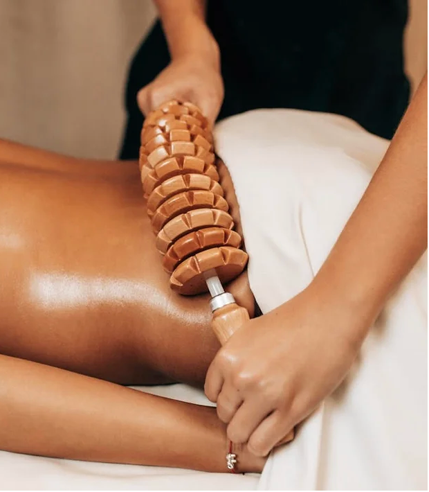A woman is getting a massage with wooden sticks on her back.
