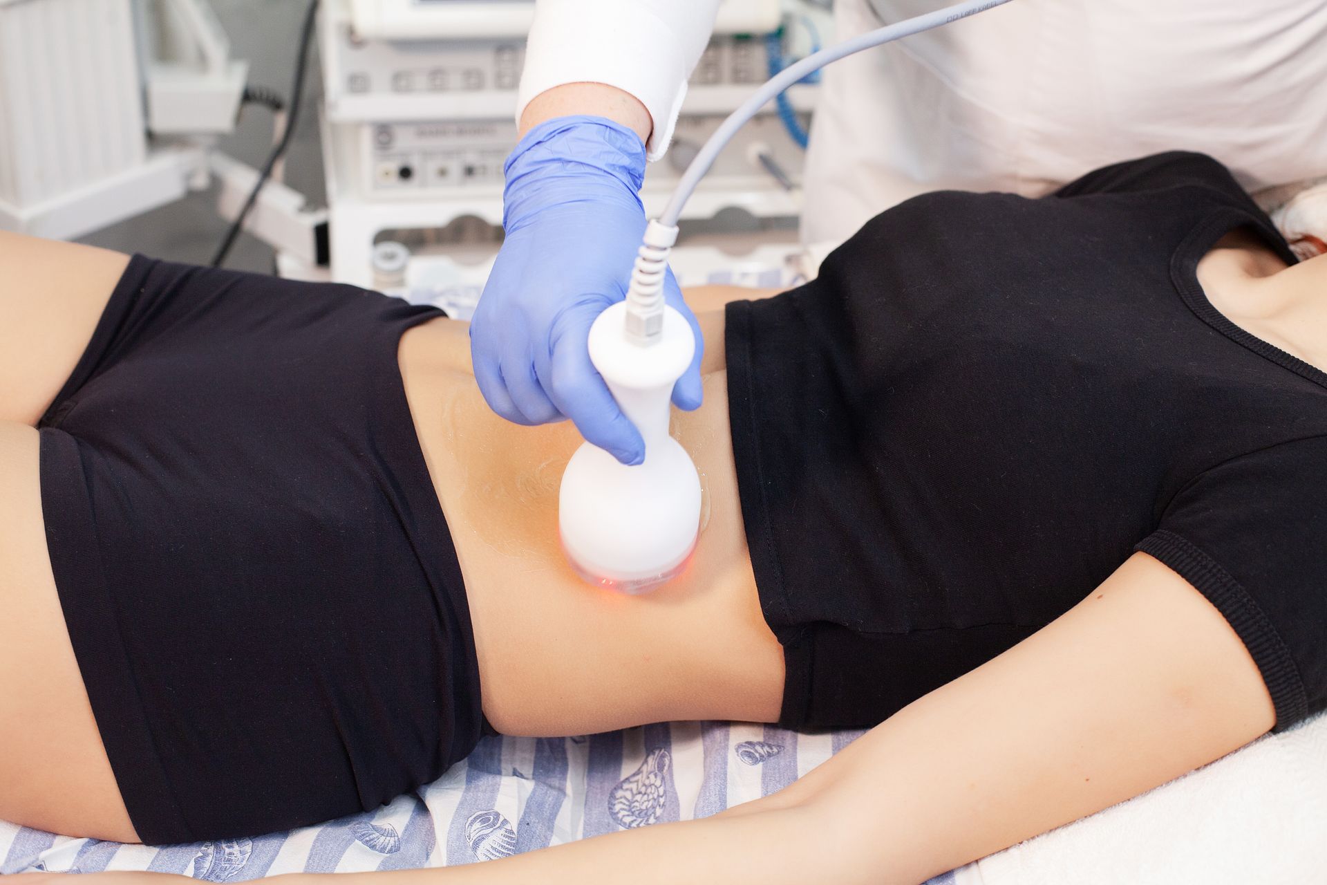 A woman is getting a cavitation treatment on her stomach.