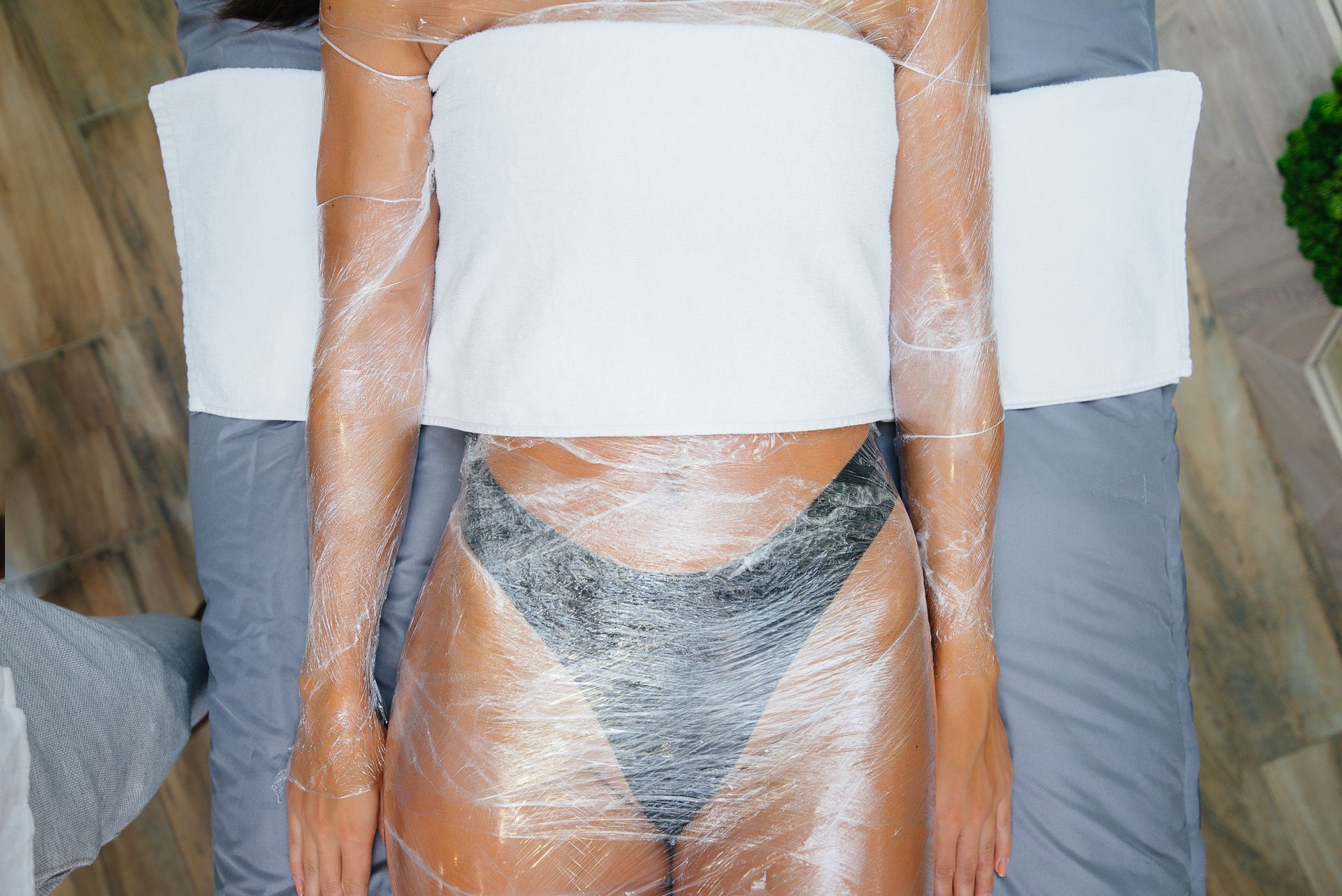 A woman is wrapped in plastic wrap at a spa.