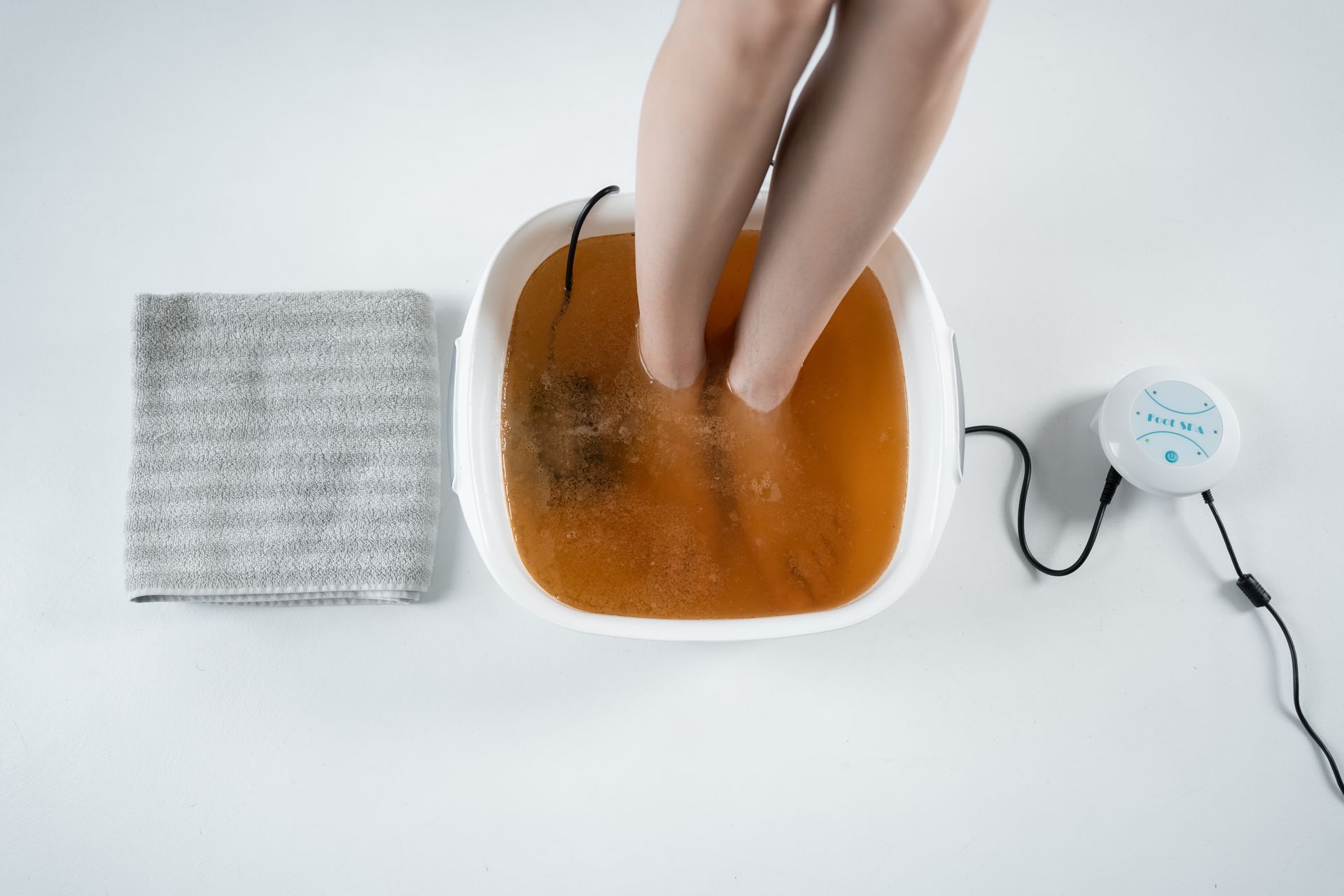 A person is sitting in a bowl of water with their feet in it.