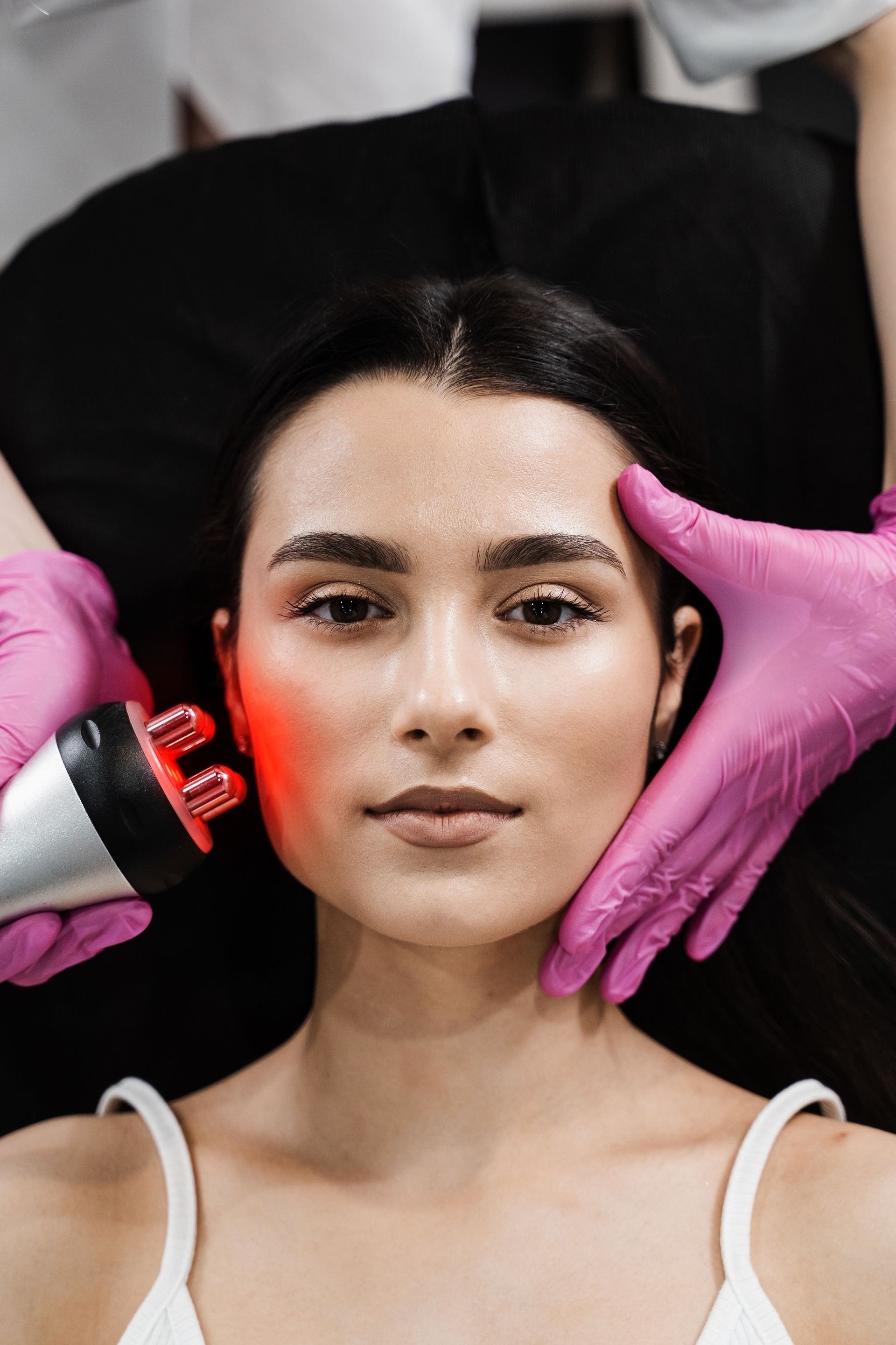 A woman is getting a red light treatment on her face.
