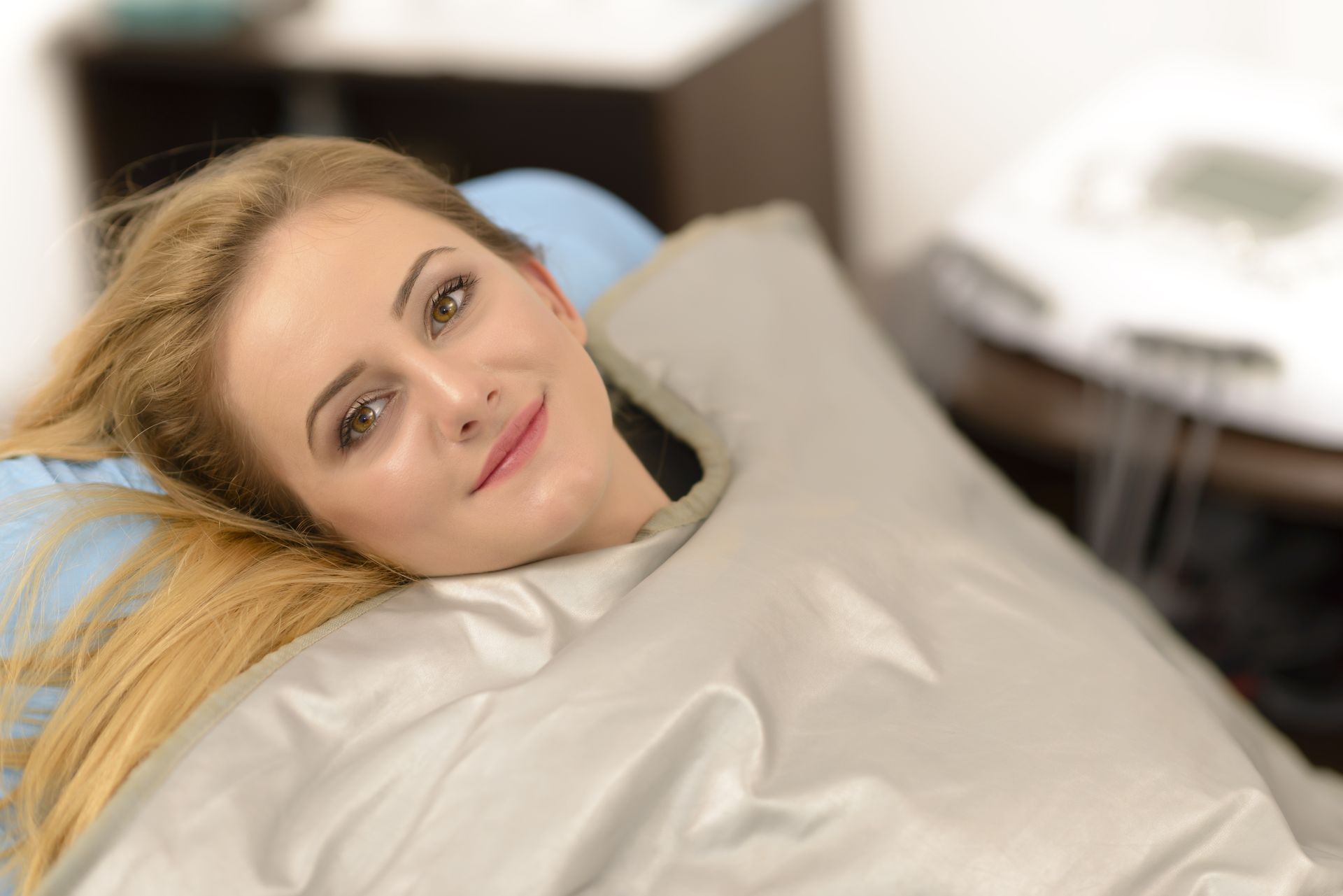 A woman is laying in a sauna blanket in a spa.