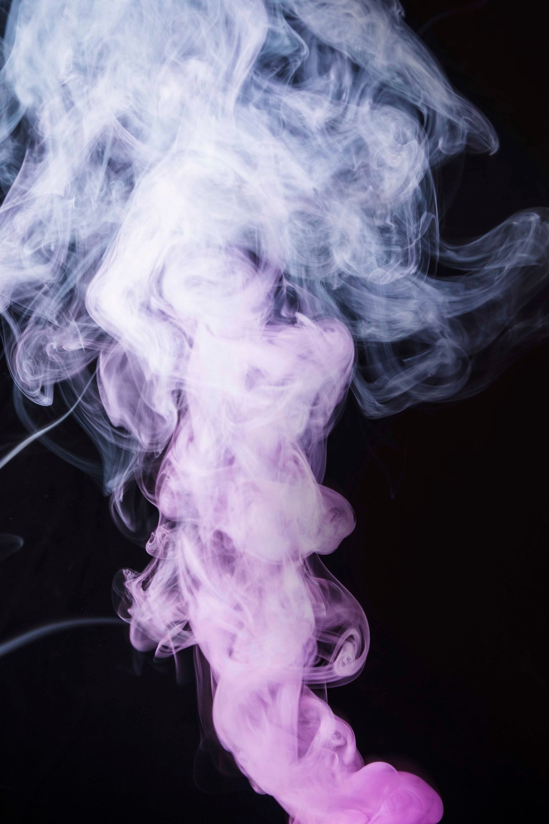 A close up of purple and white smoke on a black background.