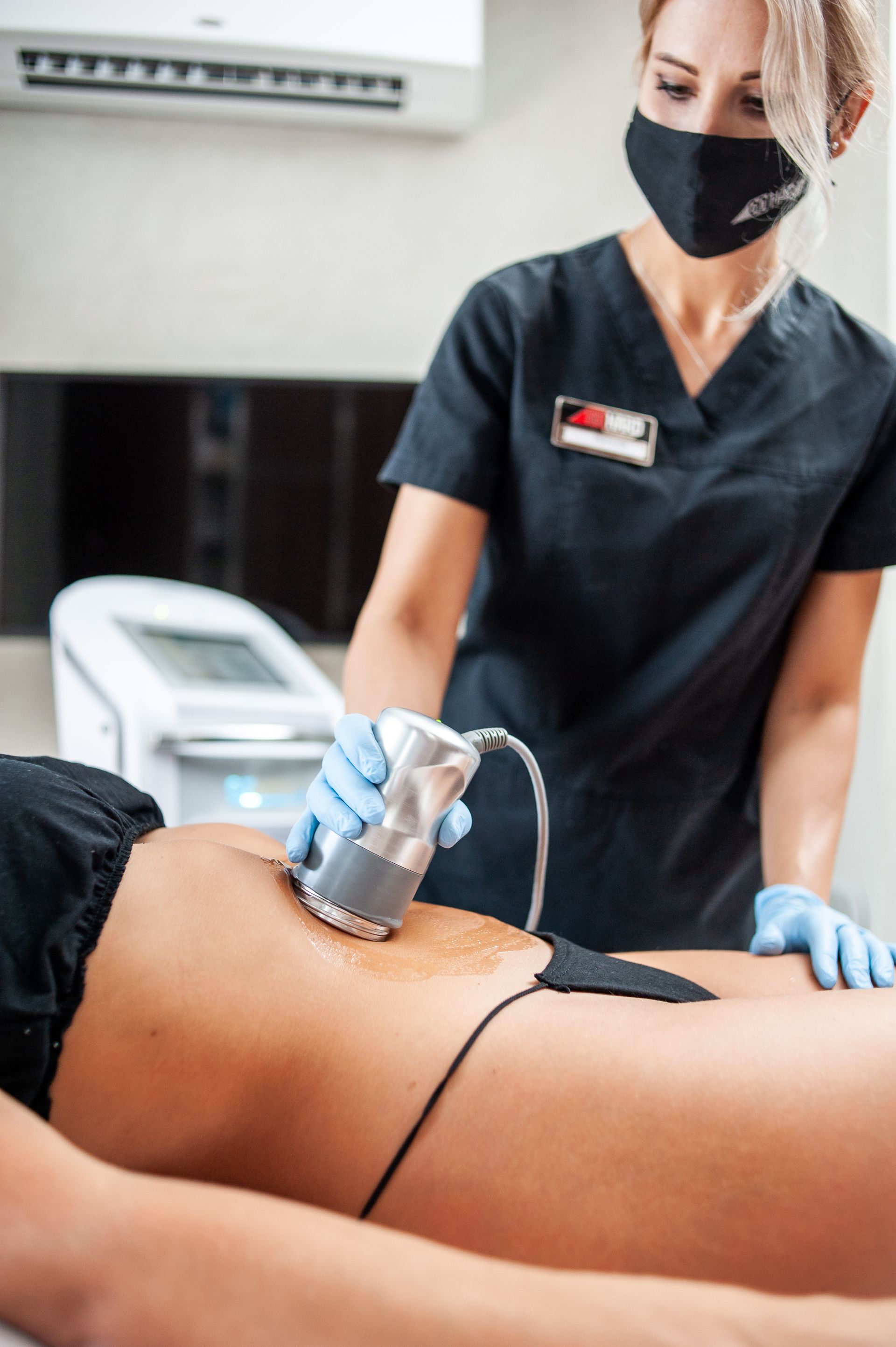 A woman is getting a cavitation treatment on her stomach.