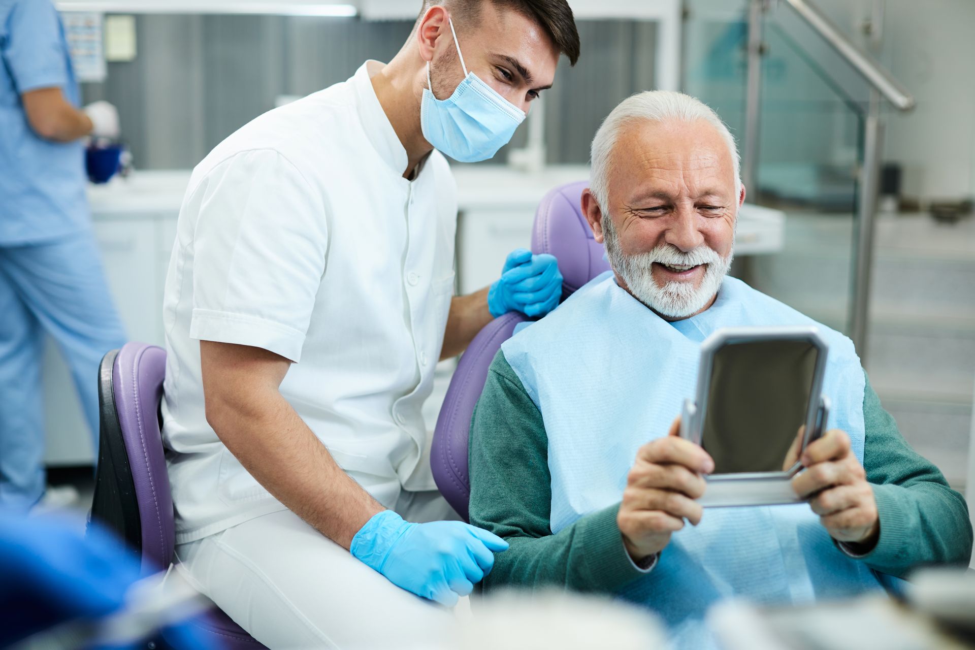 A senior man looking at his teeth in a dentist office.