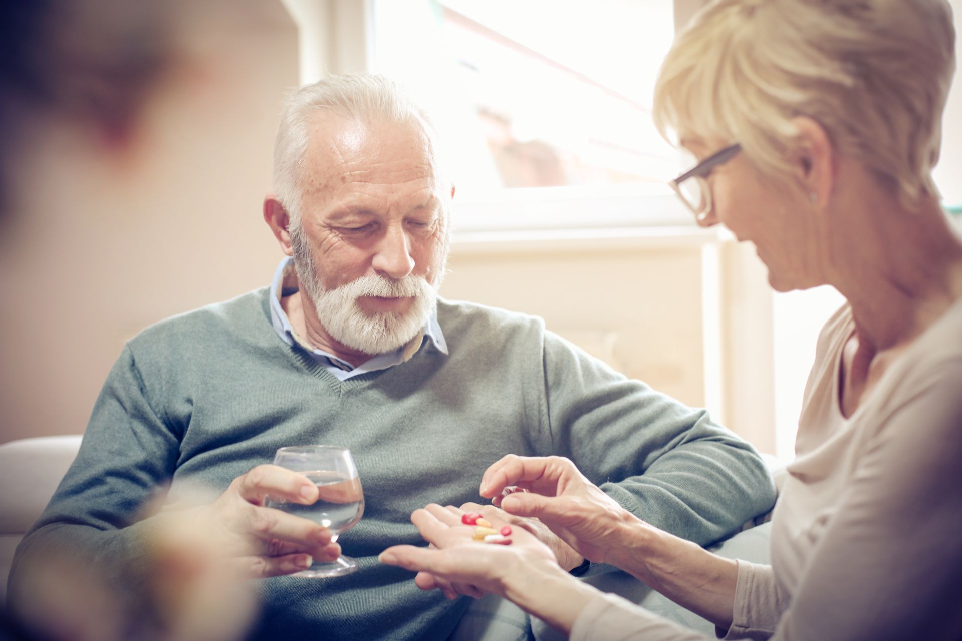 A wife giving her husband his medication.