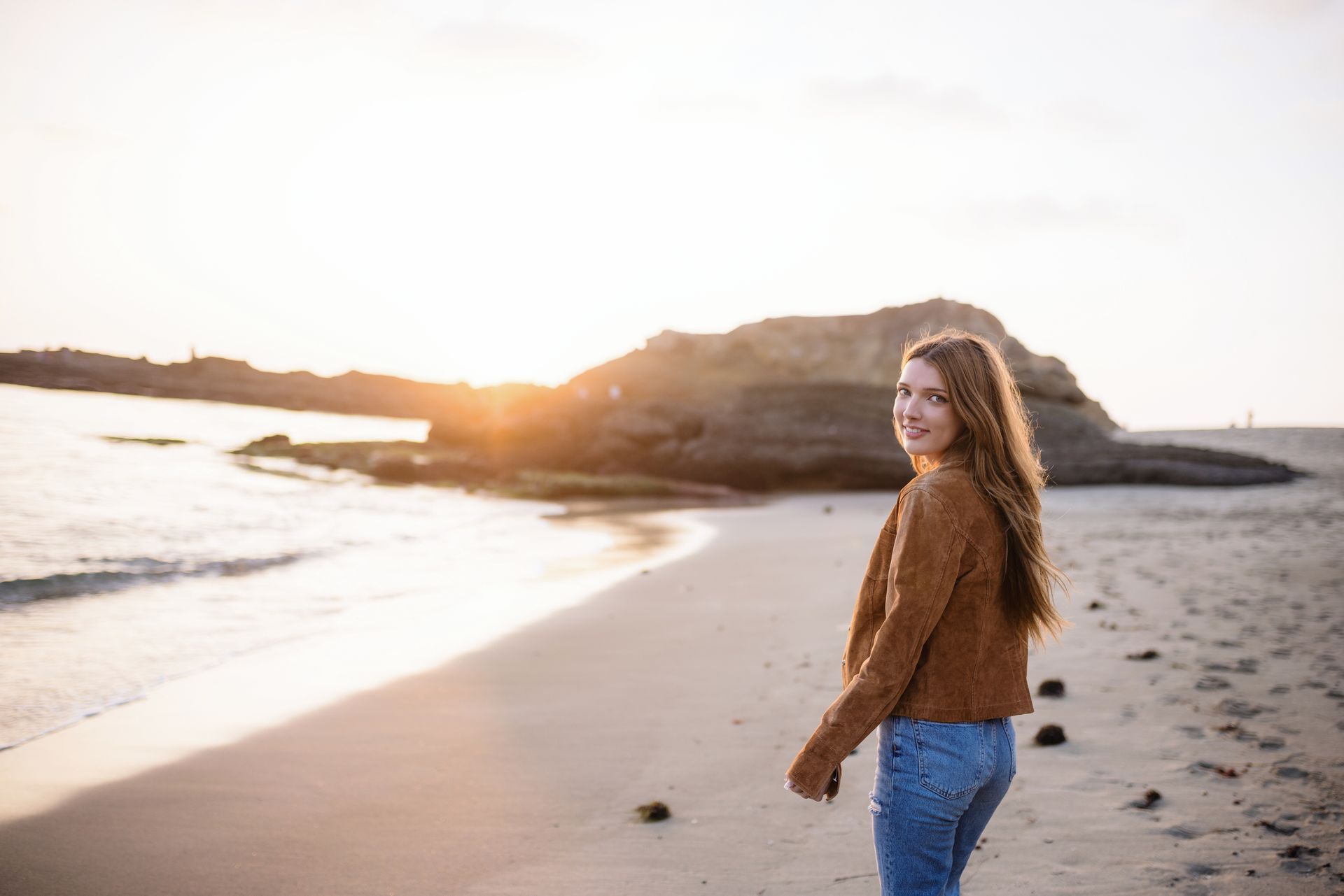 A woman is standing on a beach at sunset at the Montage beach in Laguna.