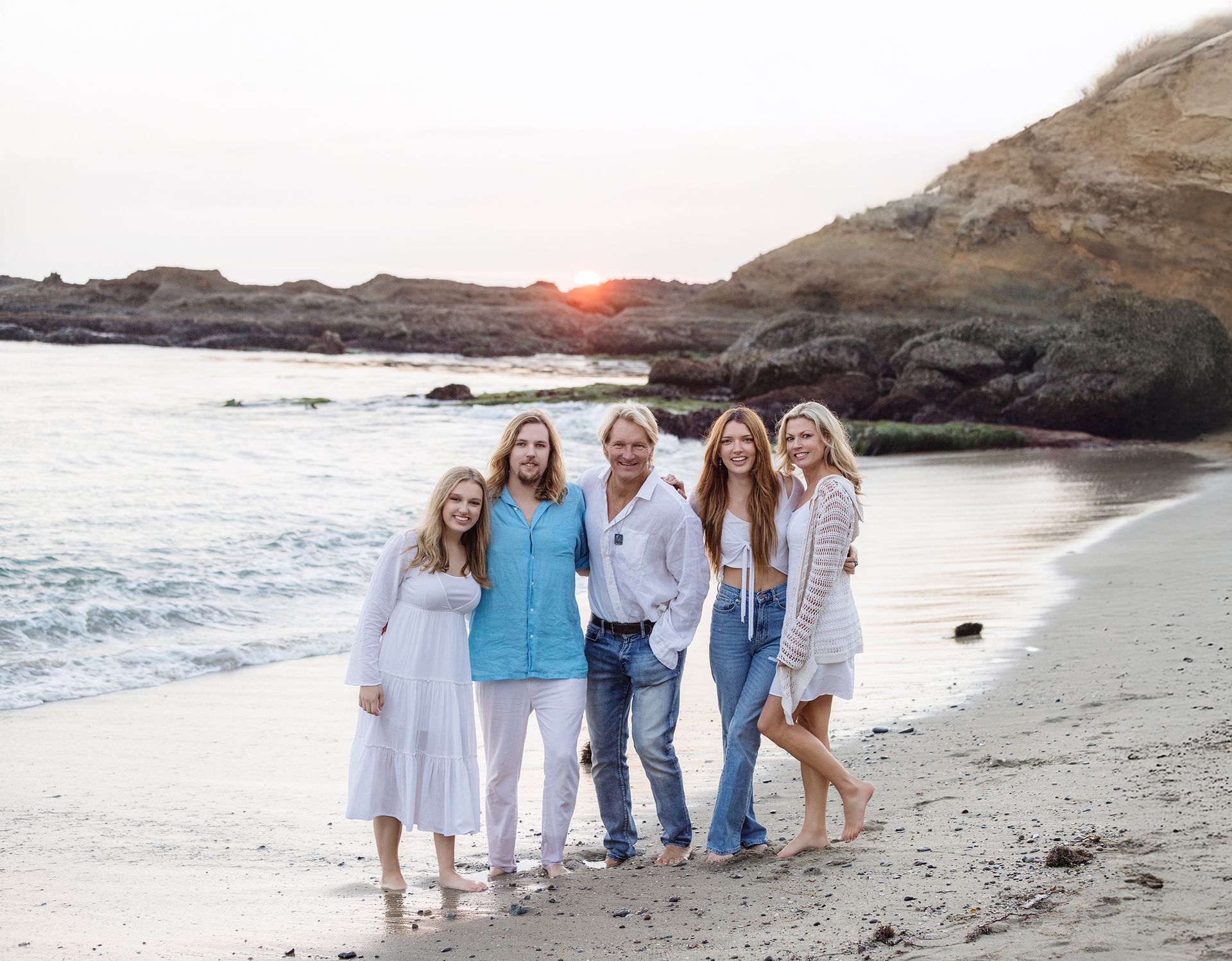 A family is posing for a picture on the beach.