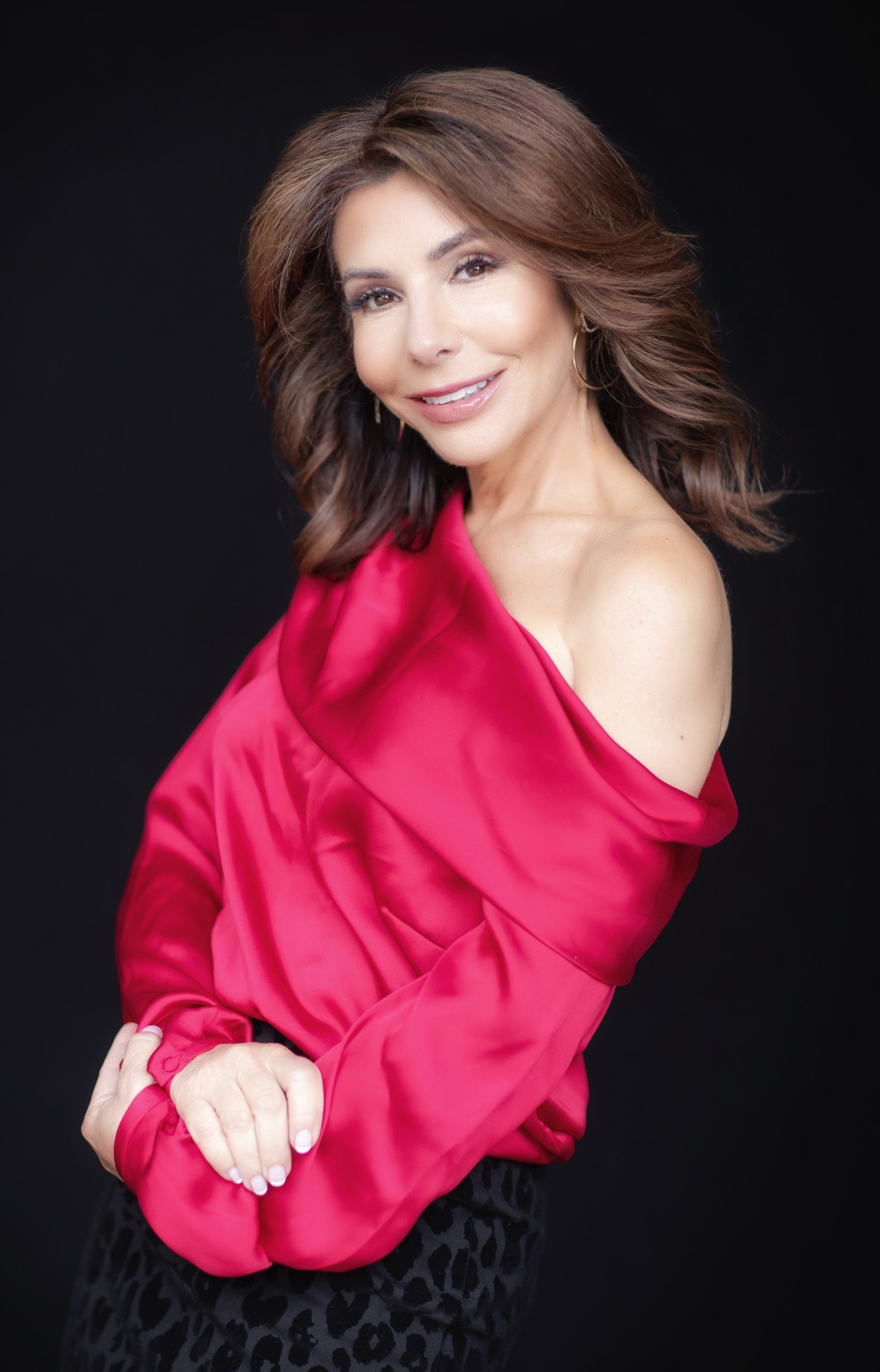 Dramatic studio branding portrait in a red satin top on a black backdrop
