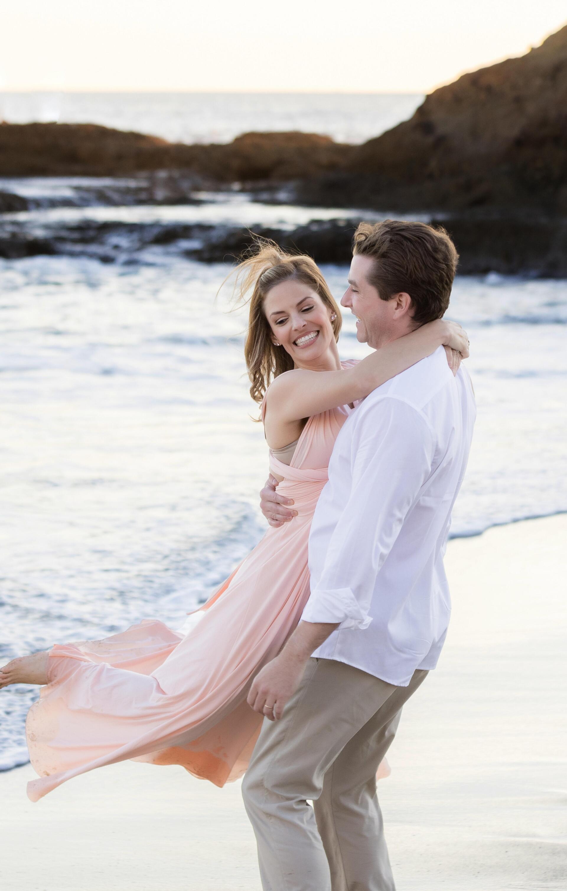 A man is holding a woman in his arms on the beach.