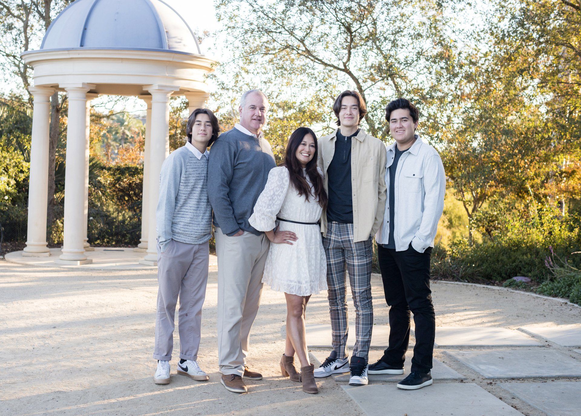 A family is posing for a picture in front of a gazebo.