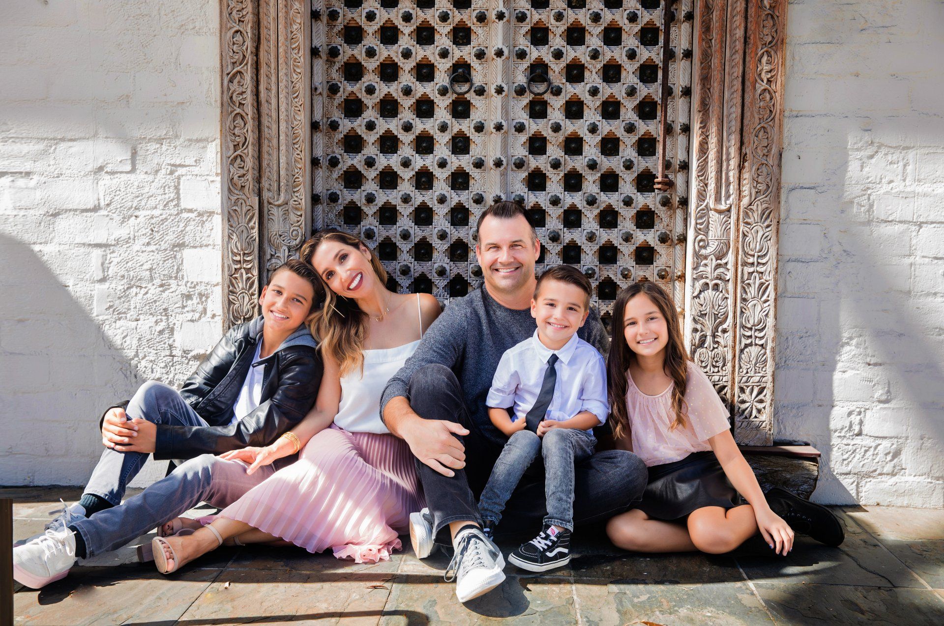 A family is posing for a picture while sitting on the ground in front of a building.