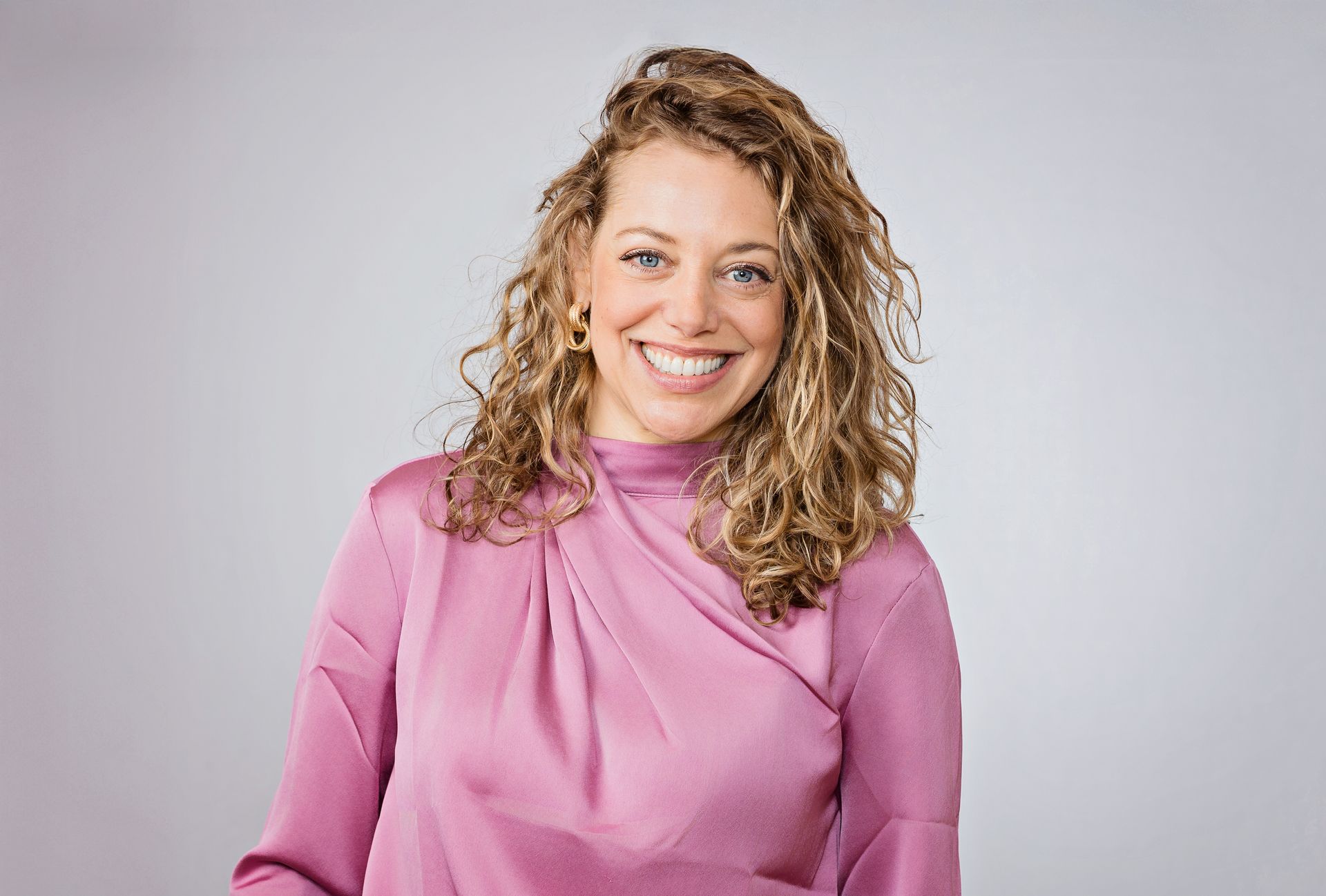 A woman in a pink shirt is smiling for the camera.