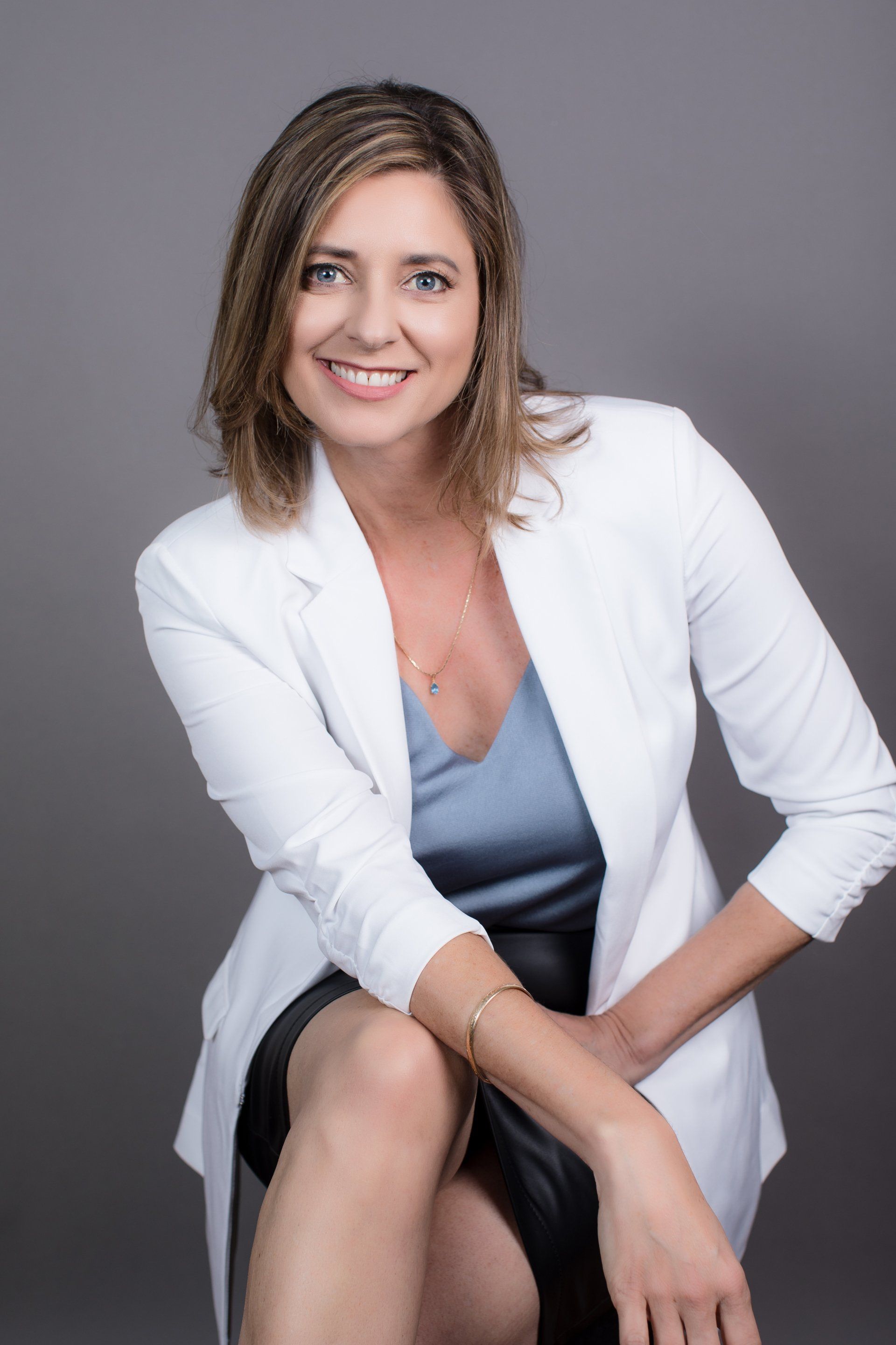 Seated real estate headshot of an agent in a white blazer
