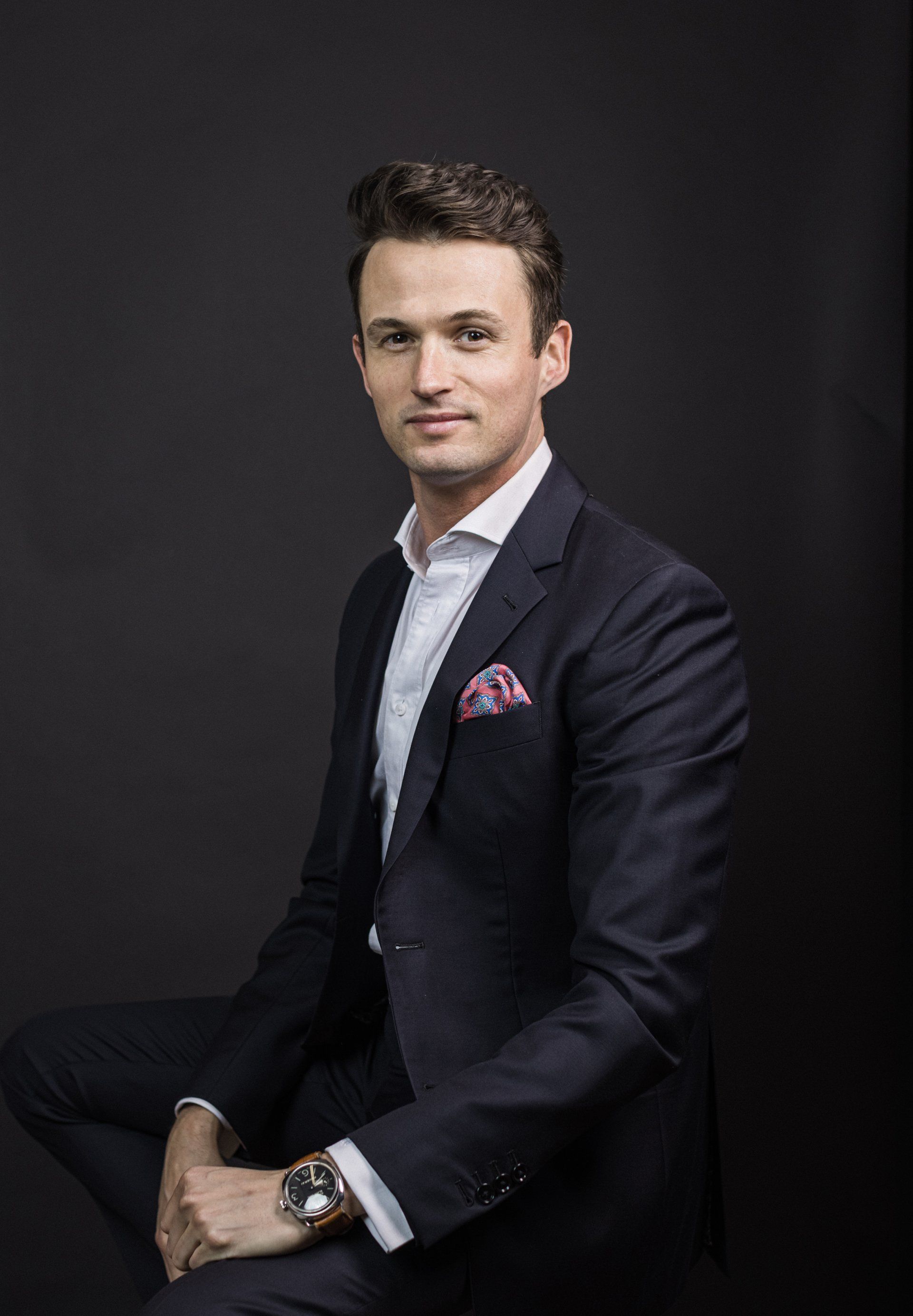 Real estate agent portrait seated on a dark backdrop