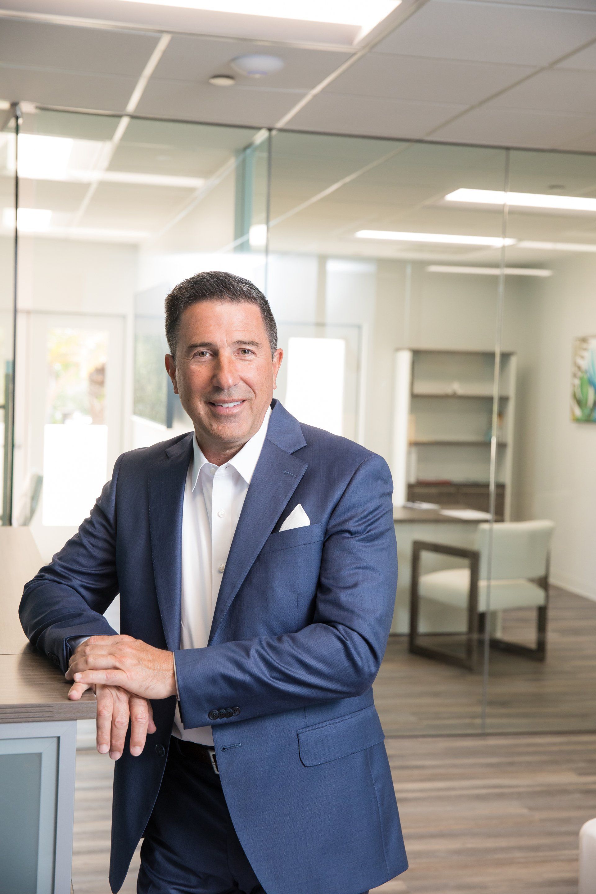 Wealth management advisor headshot in a navy suit at his Orange County office