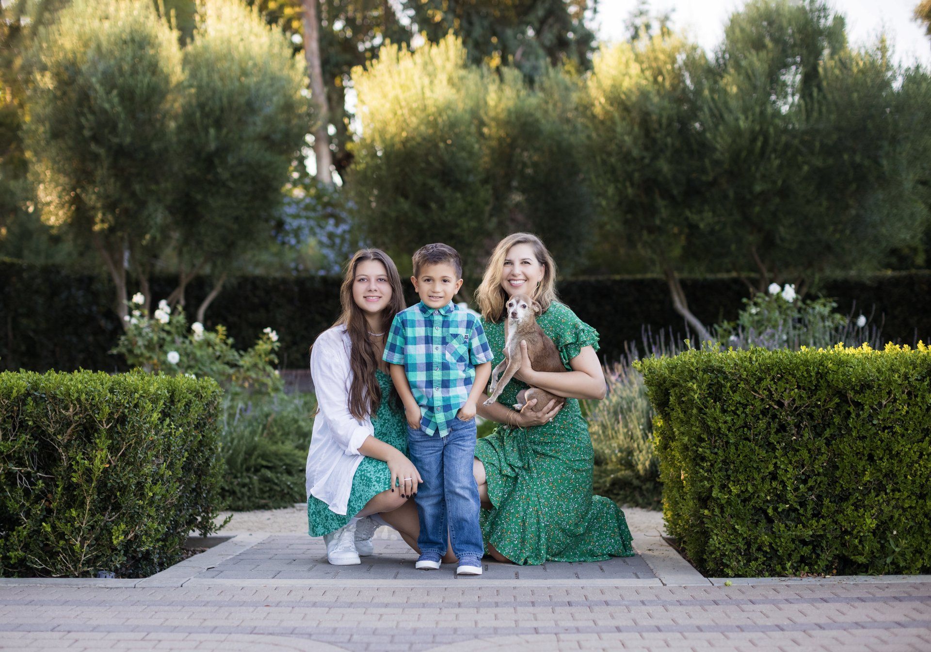 A woman and two children are posing for a picture in a park.