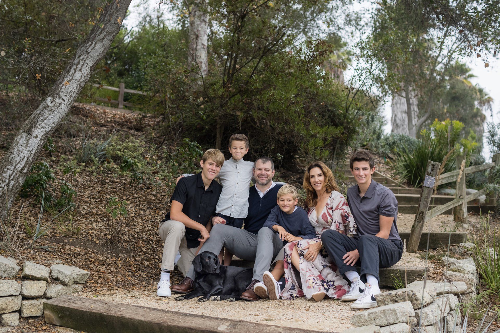 A family is posing for a picture in the woods.