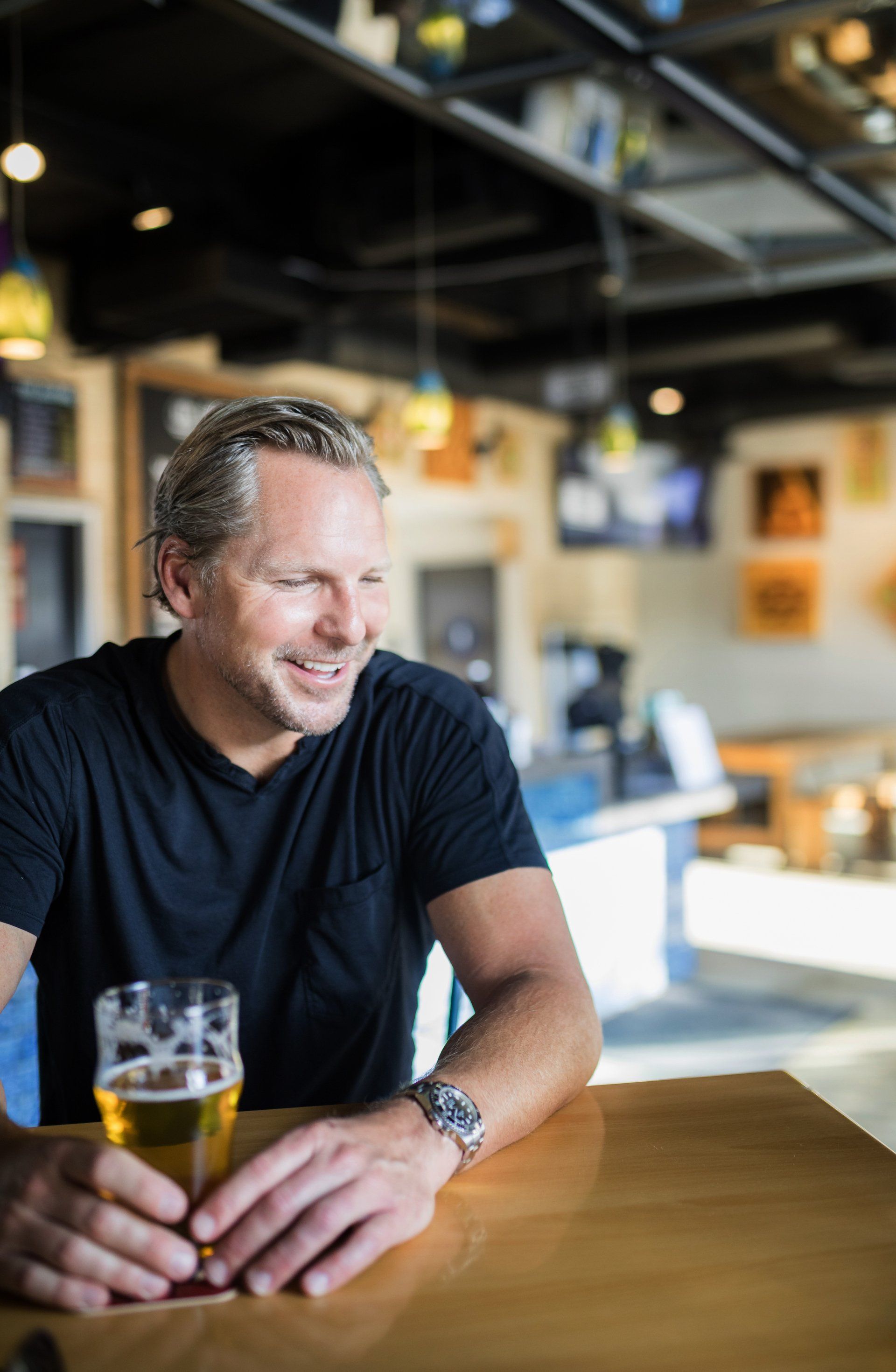 A man is sitting at a table holding a glass of beer.