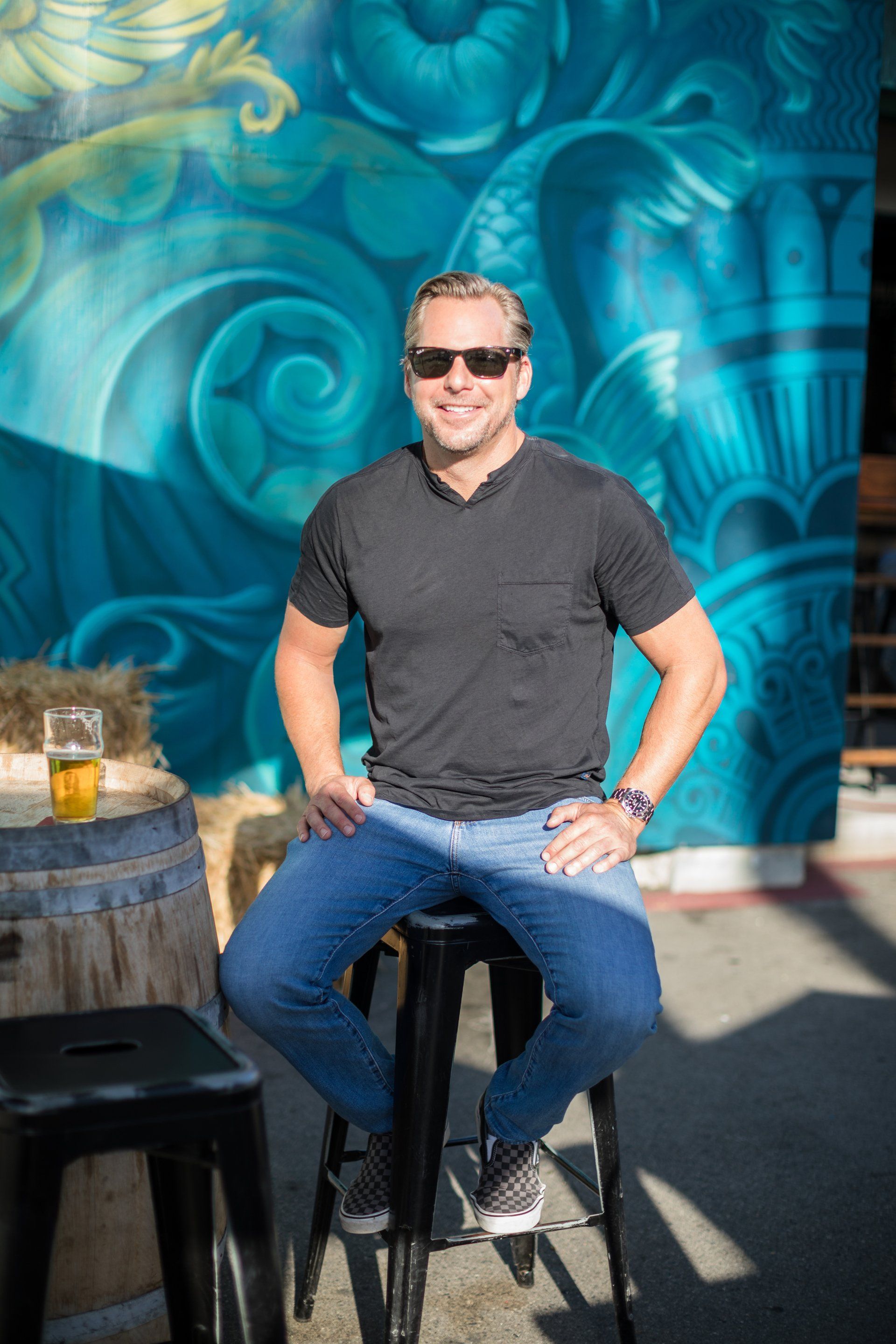 A man is sitting on a stool in front of a mural.