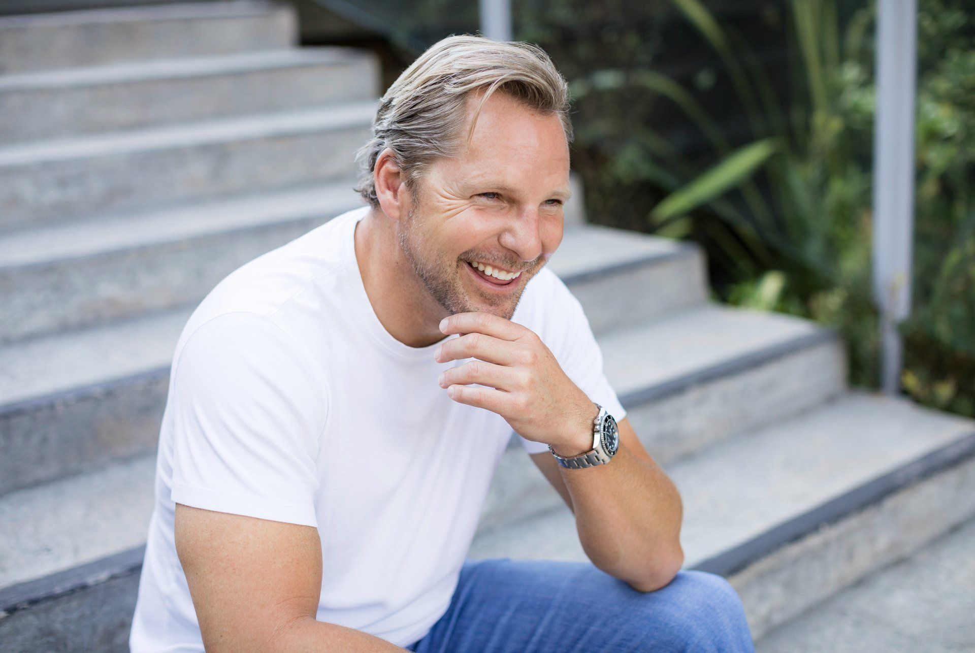 A man is sitting on a set of stairs and smiling.