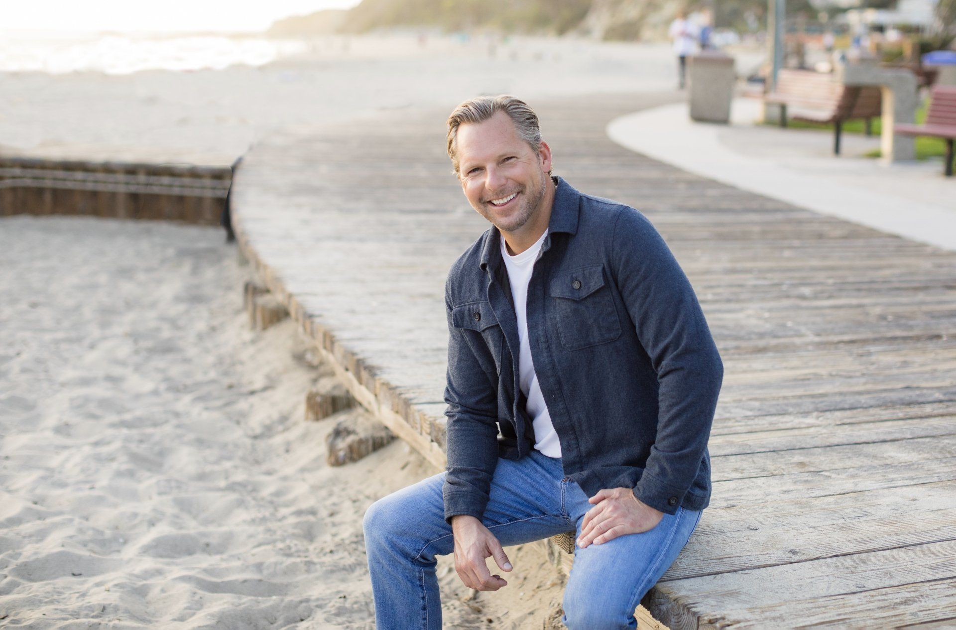 A man is sitting on a log on a beach.