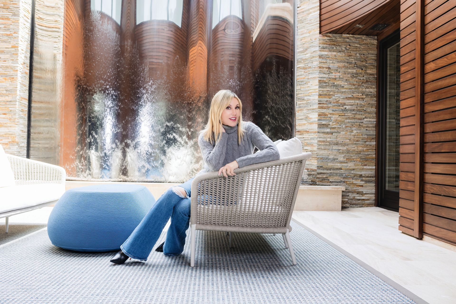 A woman is sitting on a couch in front of a fountain.