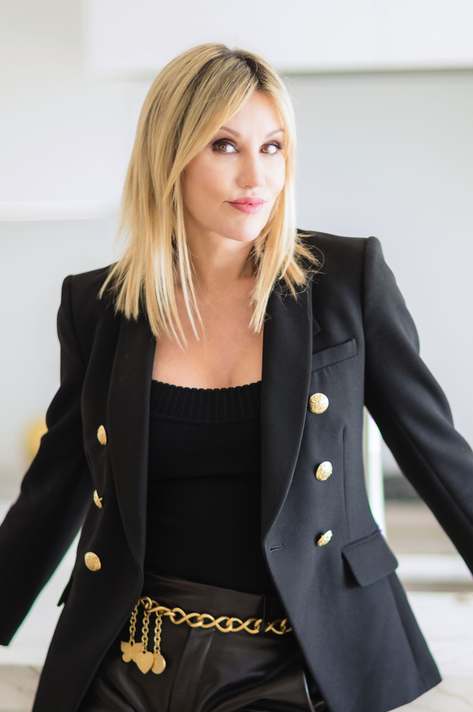 A woman is wearing a black blazer and leather shorts.