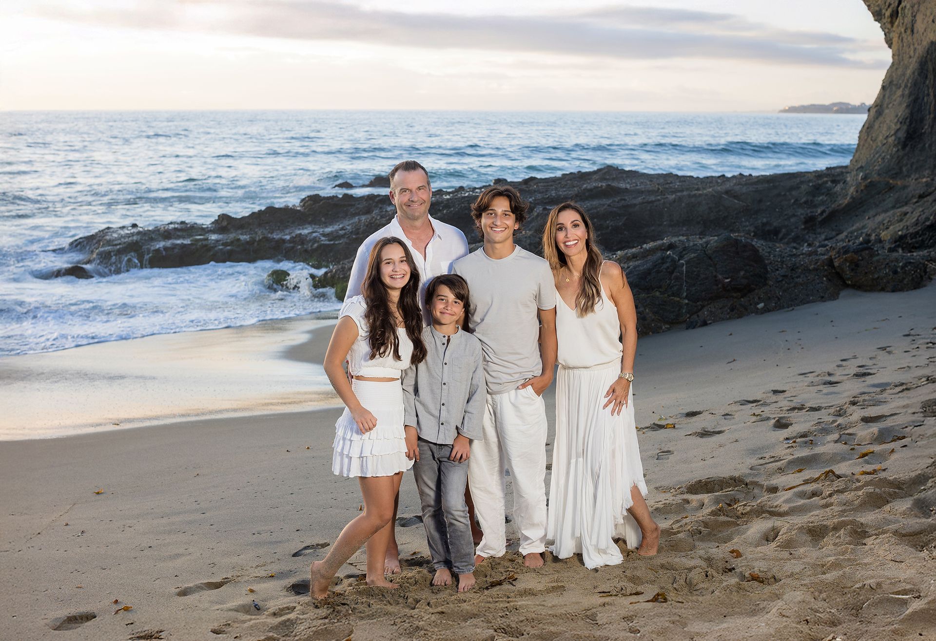 Family portrait of five at Goff Point at the Montage Resort in Laguna Beach. Entire family dressed in whites and shades of grey.