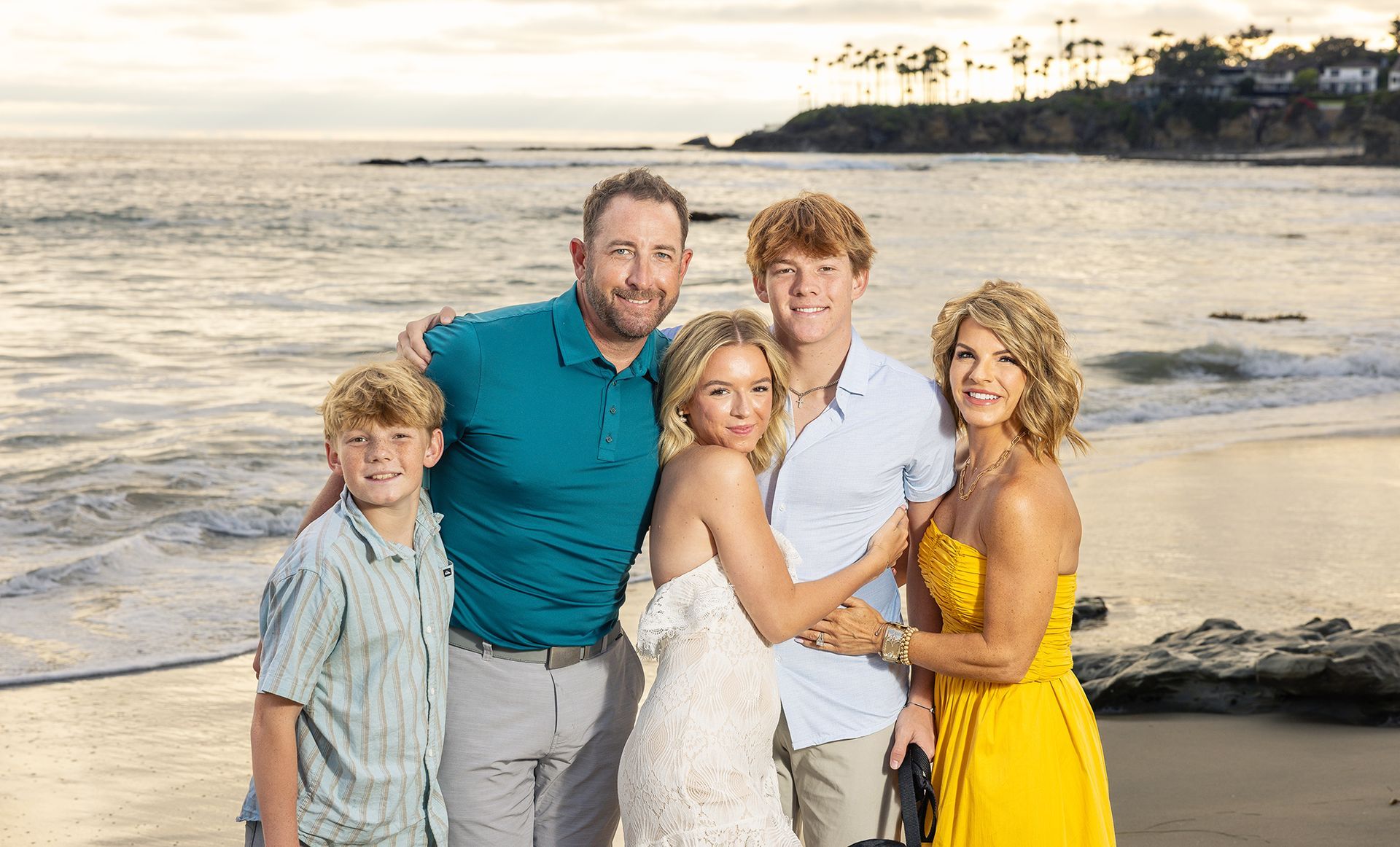 Family hugging and posing for a family portrait session at sunset in Laguna Beach.
