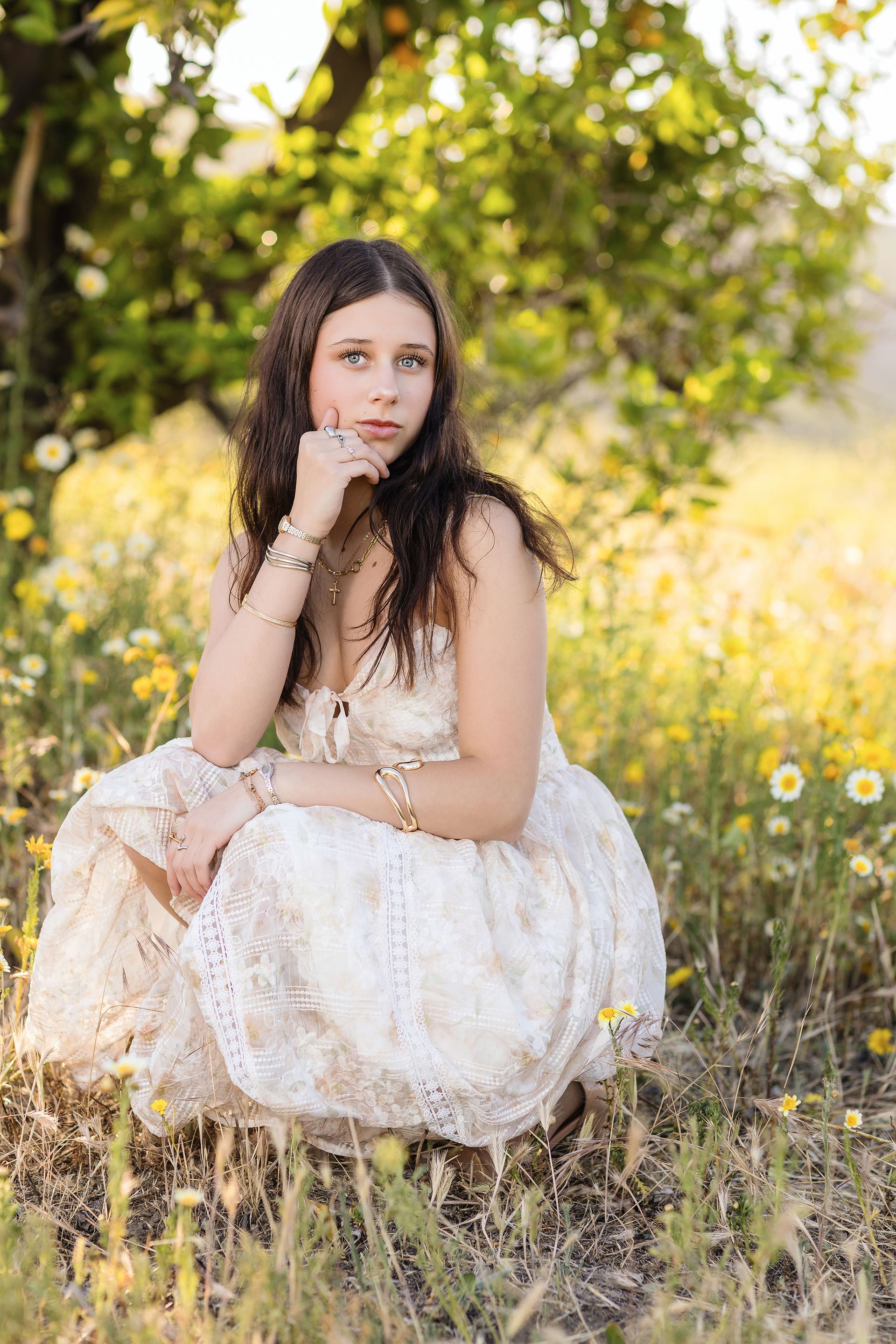 Senior girl crouching among yellow and white wildflowers in an Orange County field