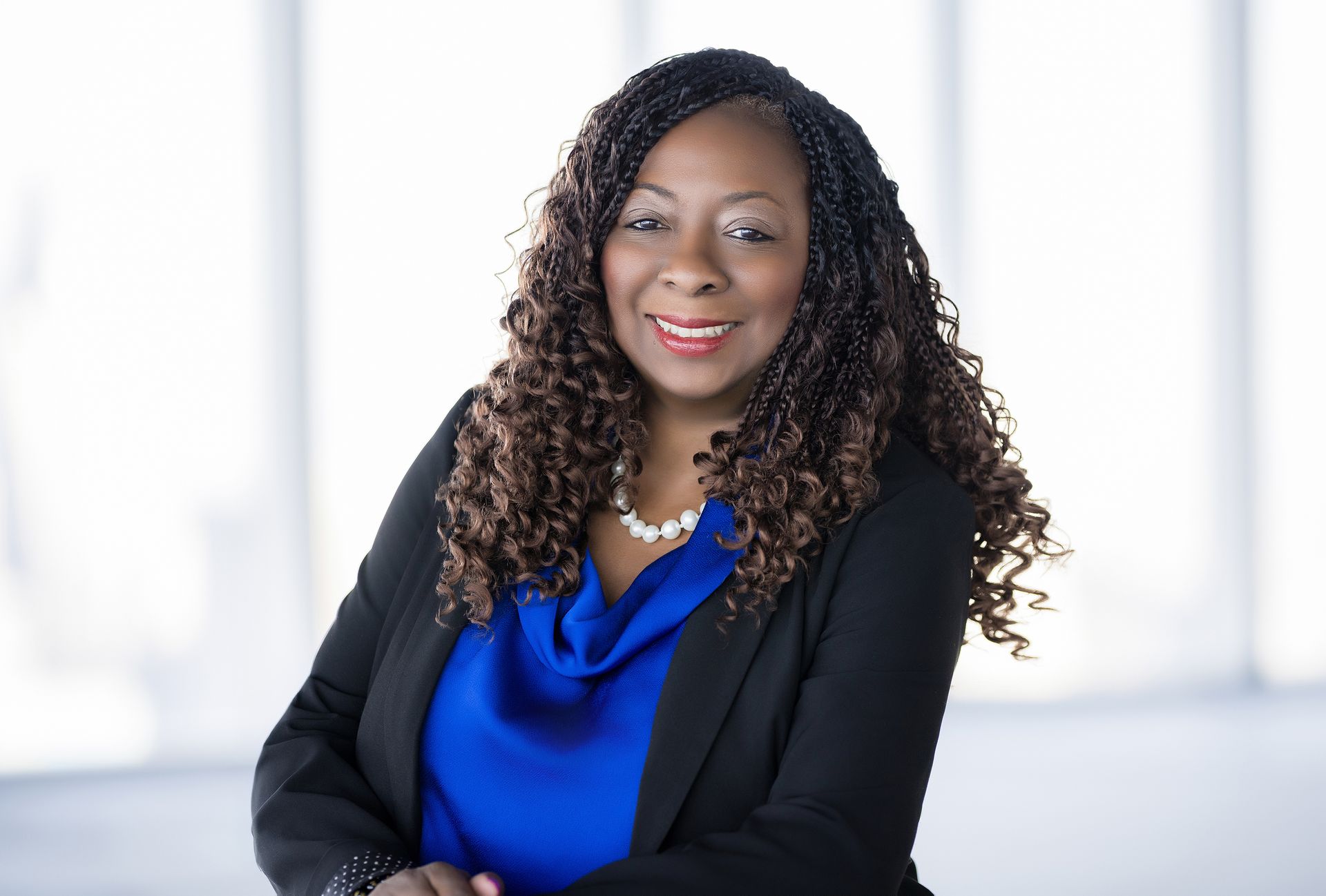 A woman in a blue shirt and black jacket is smiling for the camera.