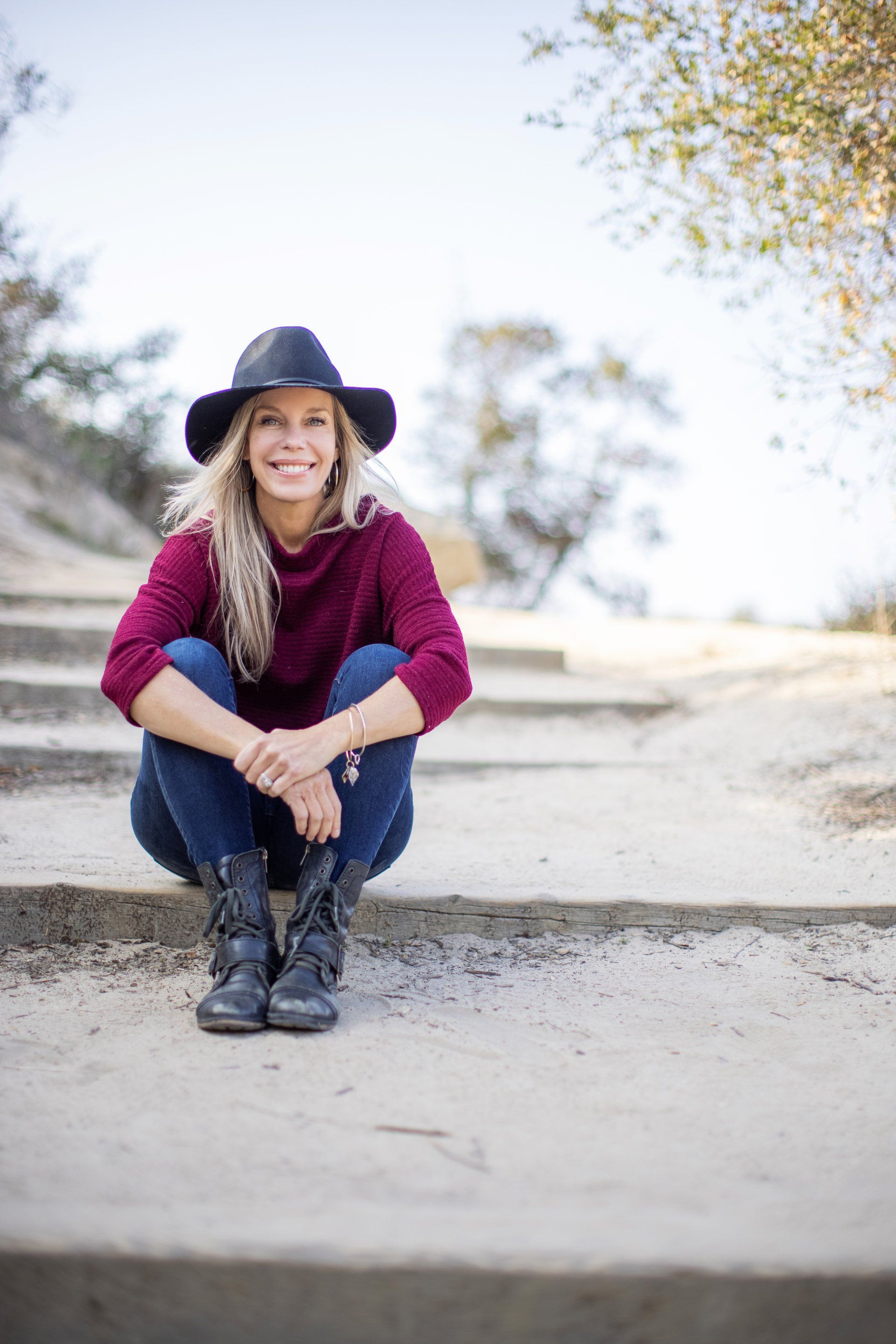 Wellness coach in a hat sitting on sandy steps