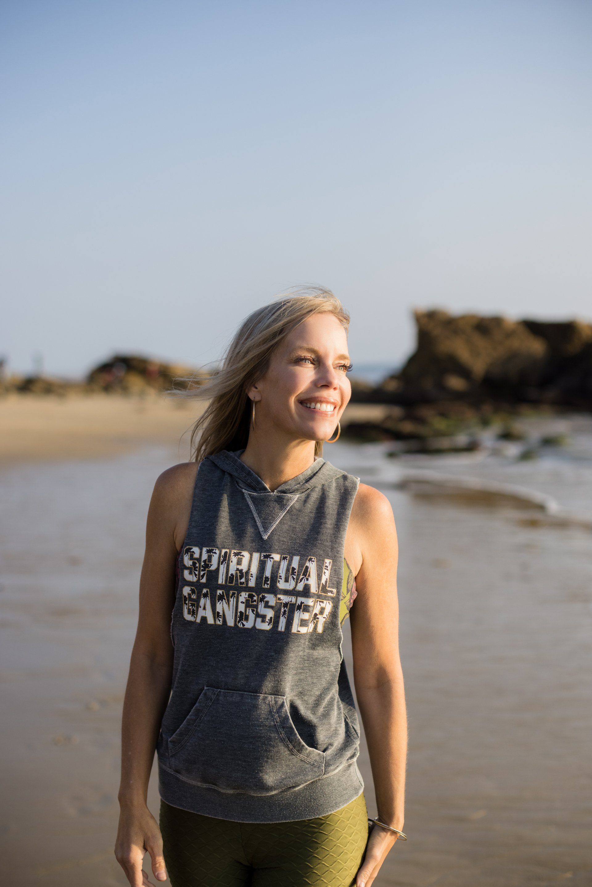 A woman is standing on a beach wearing a tank top.