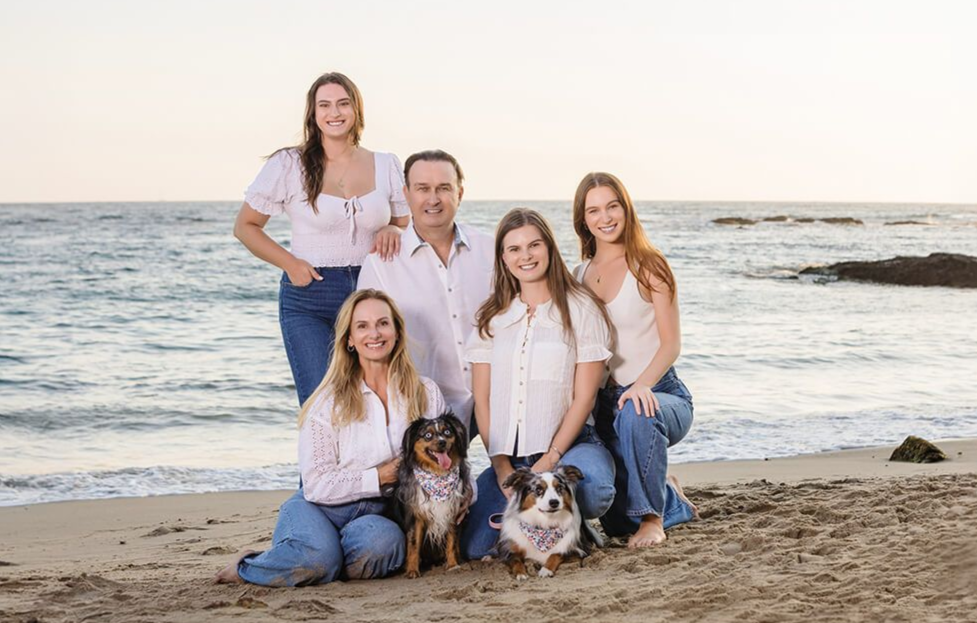 Sunset family beach portrait in Laguna Beach featuring parents, three daughters, and two dogs