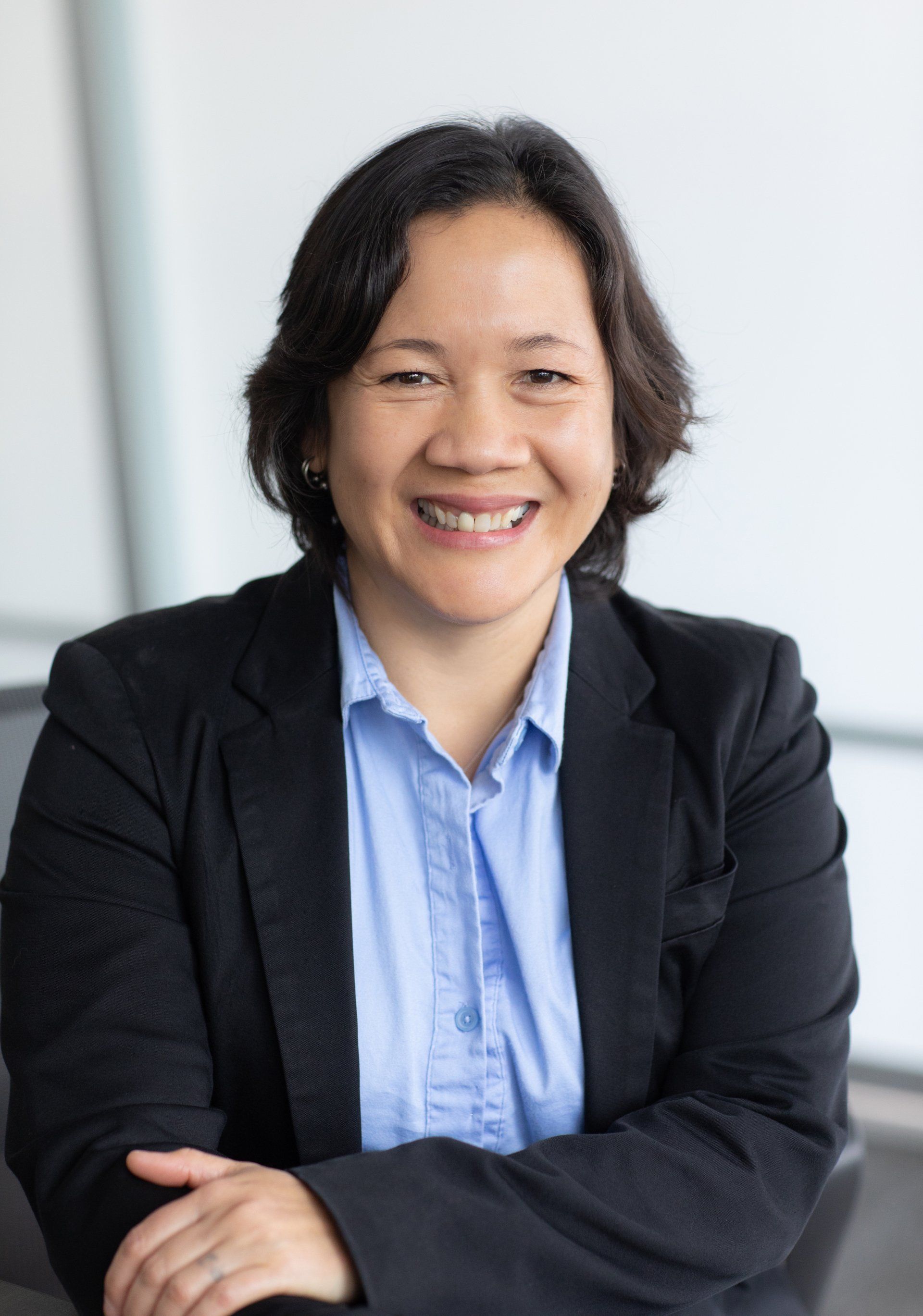 Friendly insurance professional headshot in a black blazer and blue shirt