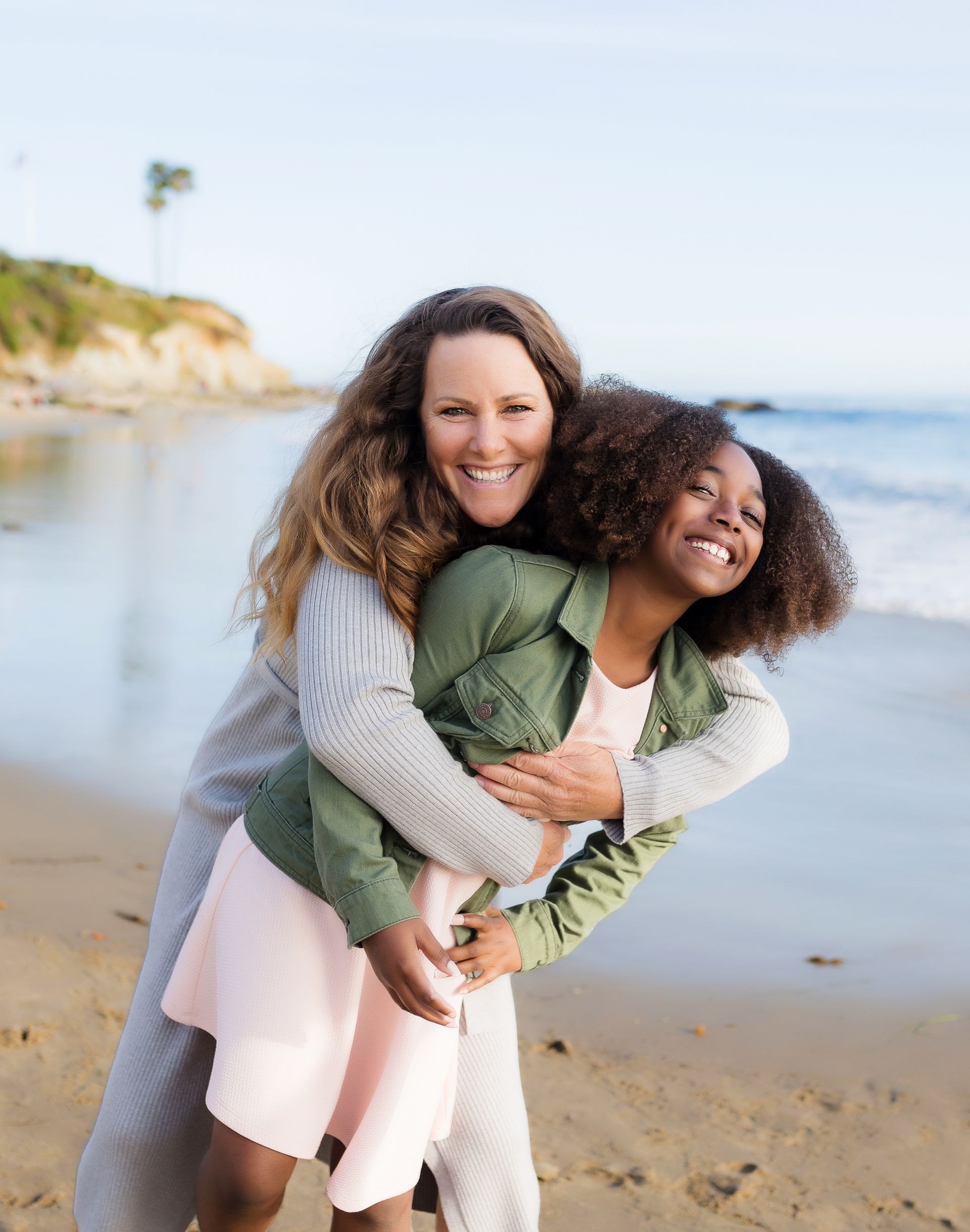 Laguna Beach family photographer — a mother and daughter embracing and laughing on the beach in Laguna Beach