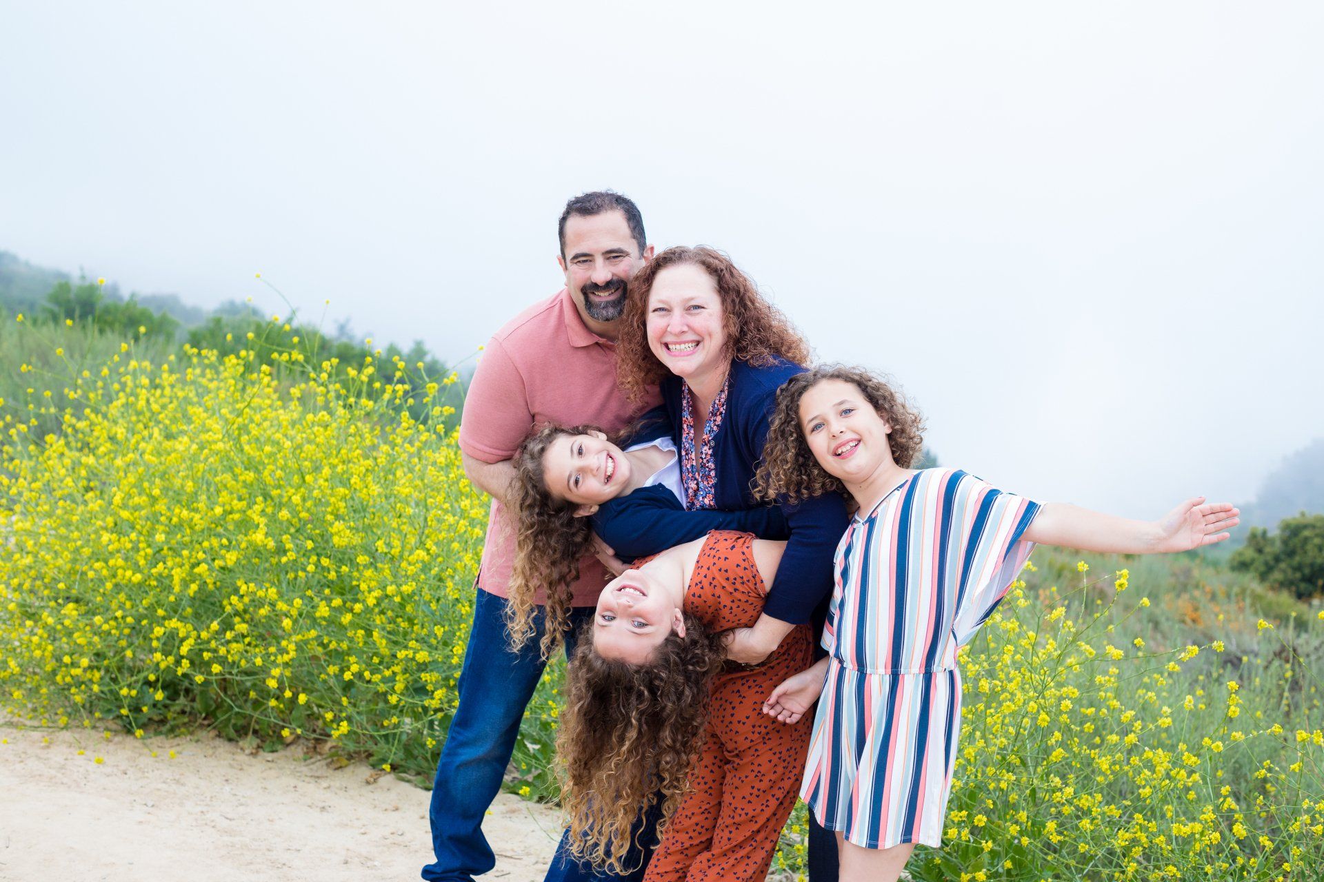 Laughing family playing in a field of yellow wildflowers in Orange County