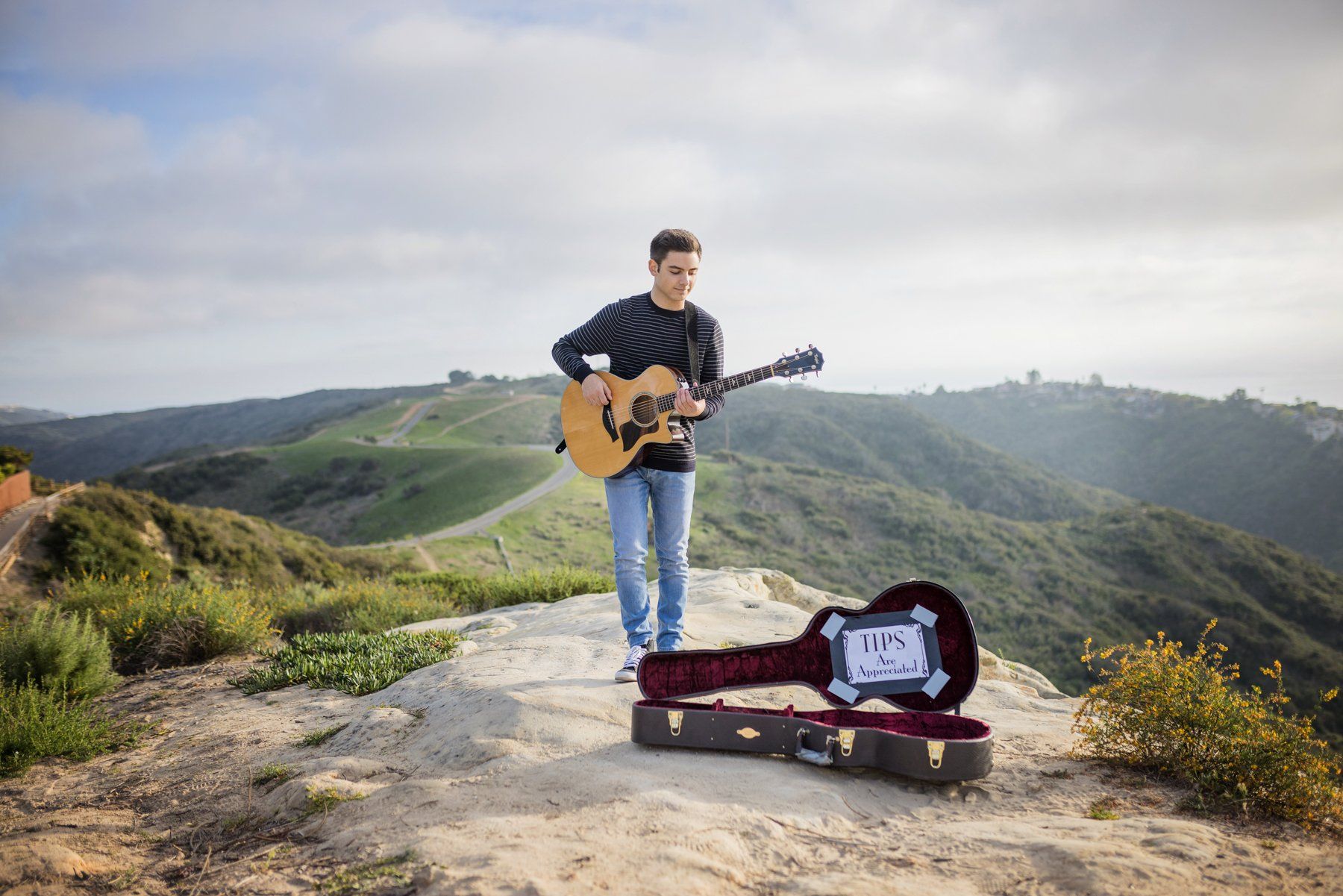 A man is playing a guitar on top of a mountain.